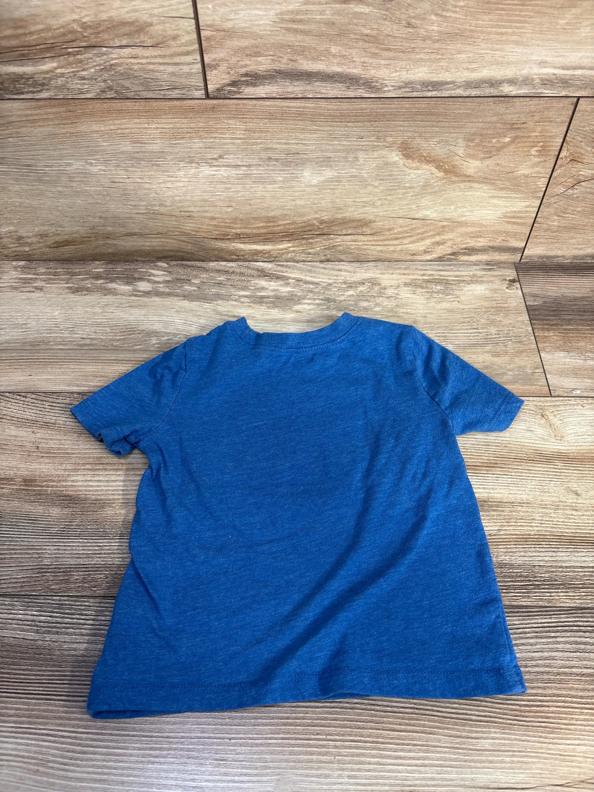 Back view of Old Navy toddler graphic tee in size 2T showcasing solid blue fabric and short sleeves on a wood floor