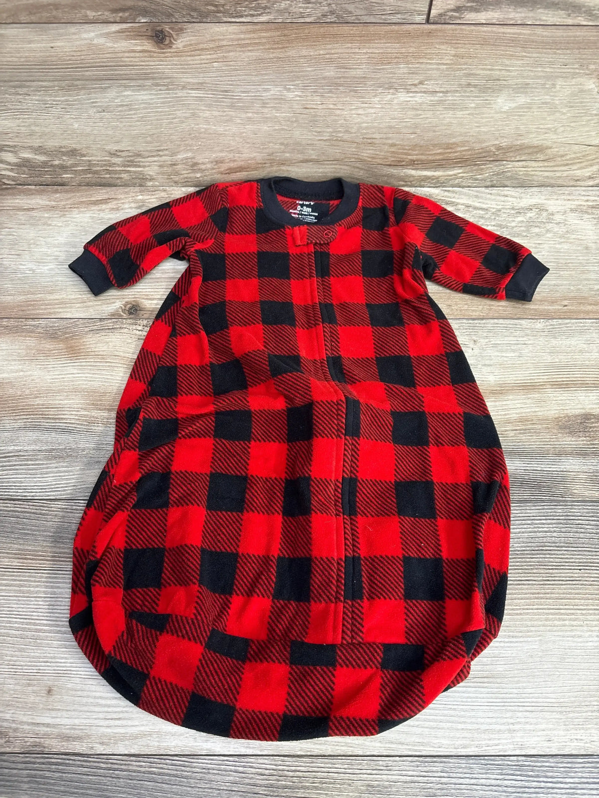 Red and black plaid infant sleep sack with zipper, long sleeves, on wood background
