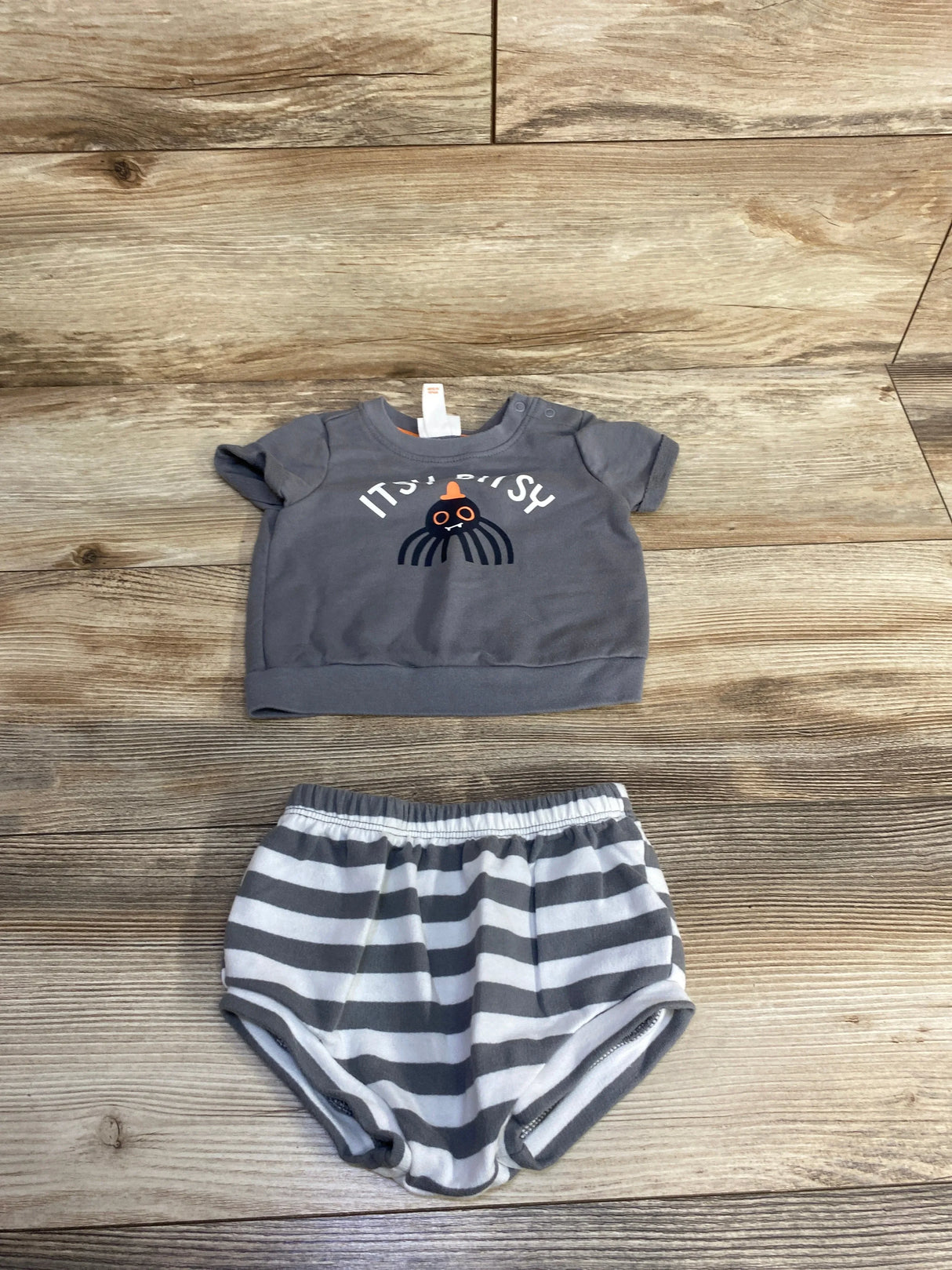 Gray baby onesie with octopus graphic and striped shorts, kids clothing set on wood floor