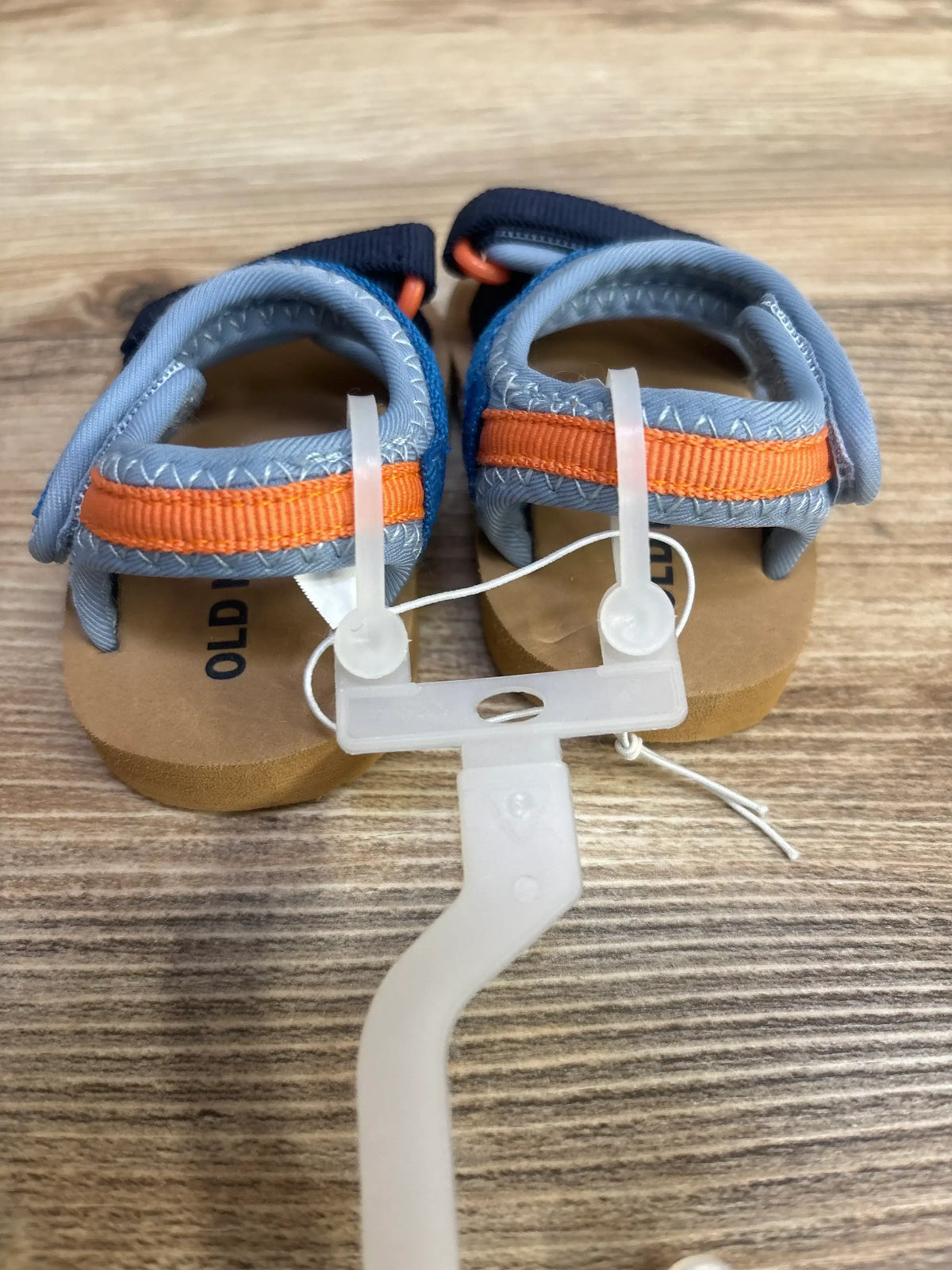 Top view of black Wonder Nation sports slides showcasing orange straps and textured footbeds on a wood surface