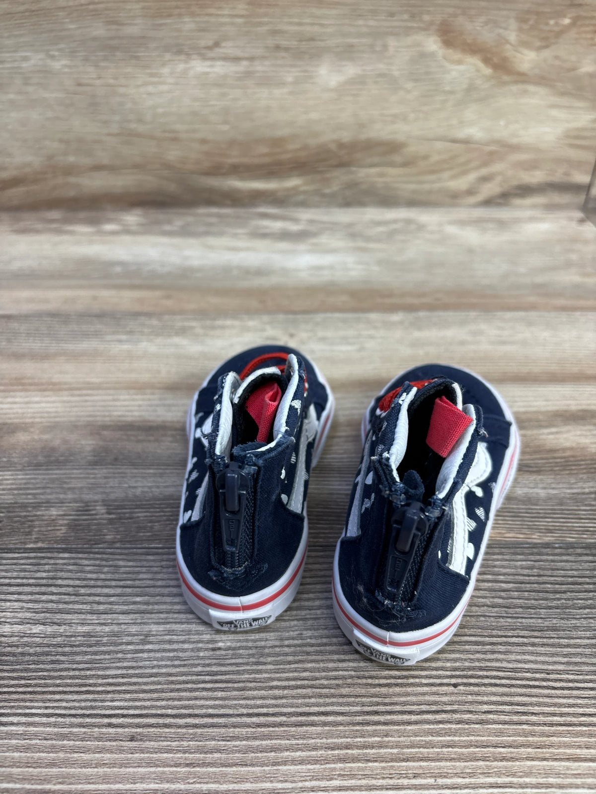 Top-front view of toddler Vans Sk8-Hi zip sneakers size 6C navy with white hearts showing front zipper on wood background
