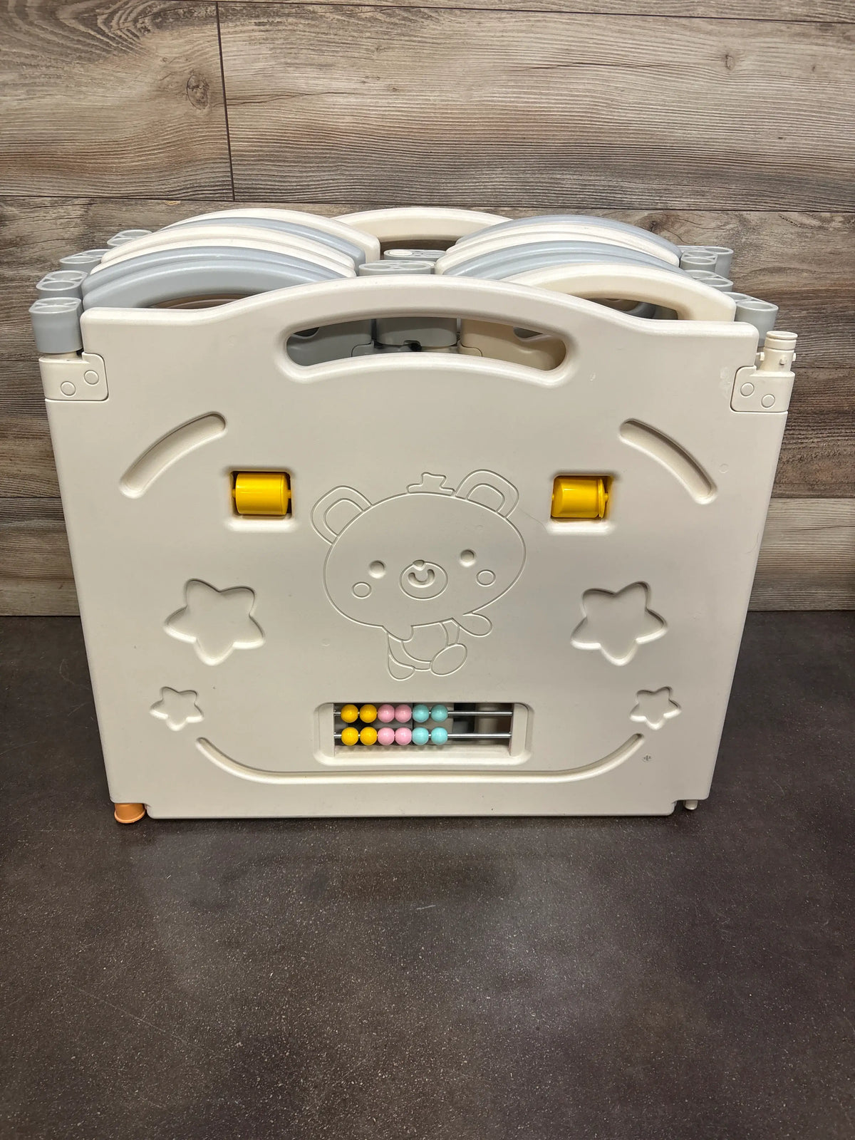 Front view of UANLAUO Foldable 14-Panel Playpen showcasing activity panel and folded panels with wood backdrop