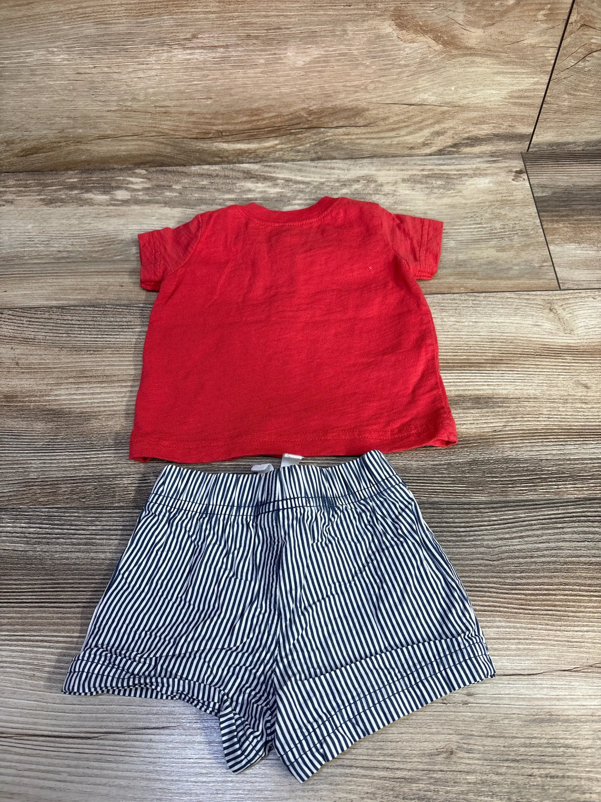 Front view of Just One You 2-piece shirt and shorts set showcasing red shirt and navy striped shorts on a wood floor