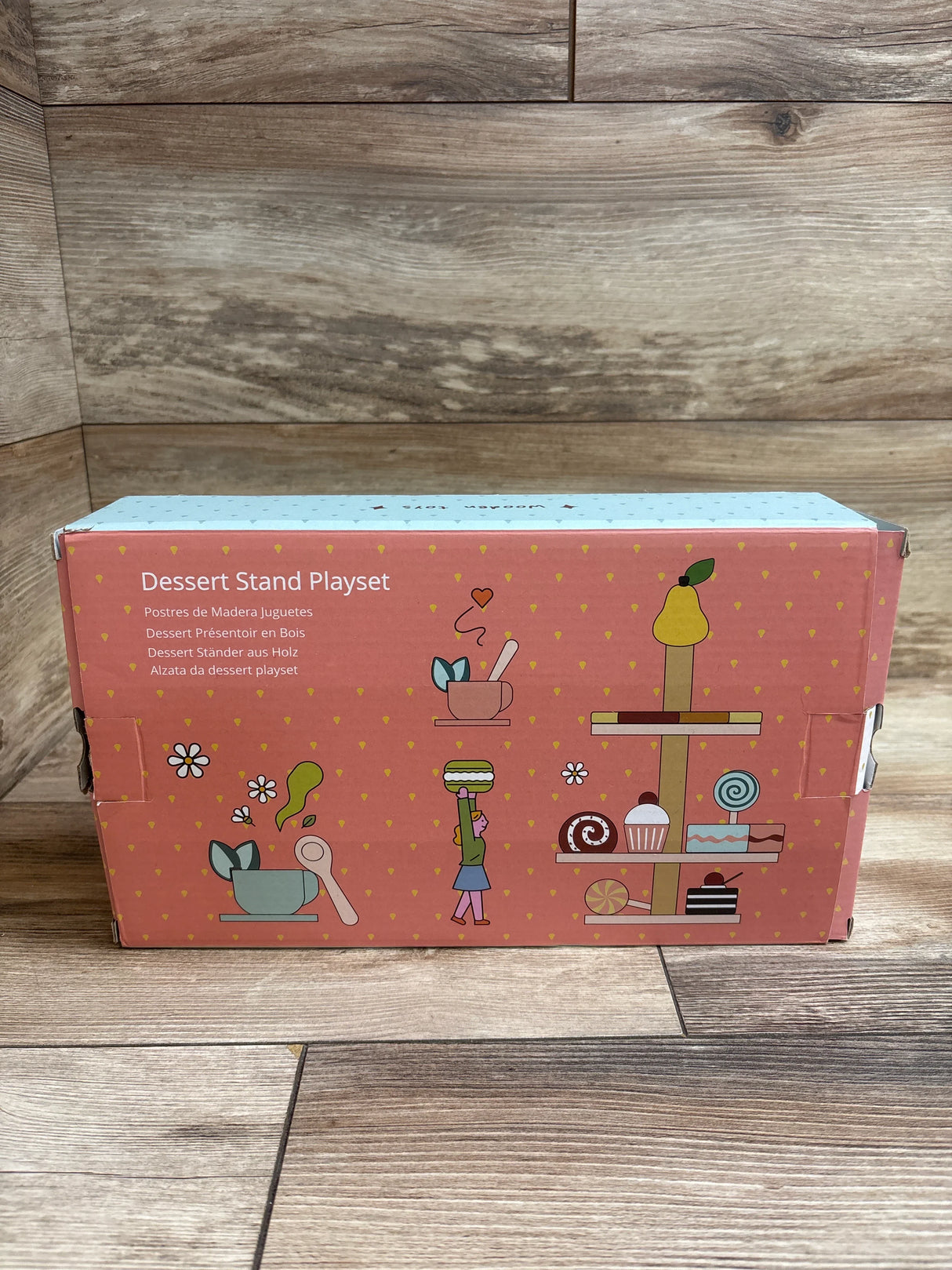 Dessert Stand Playset toy packaging with wooden dessert illustrations, on wood background