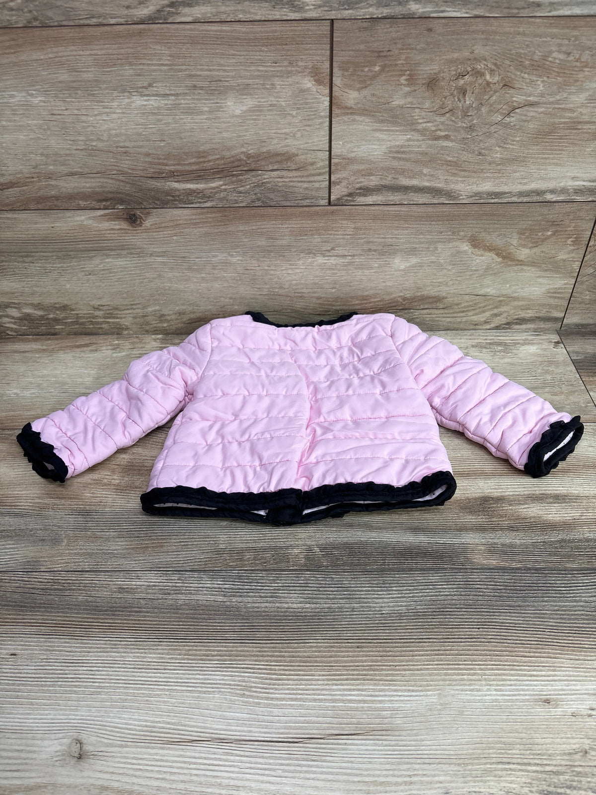 Front view of pink Little Me lightweight puffer jacket showcasing quilted panels and black trim on wood flooring