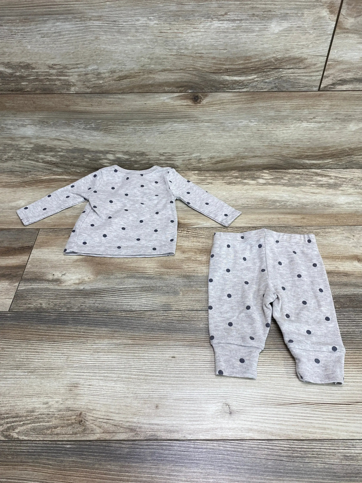 Flat lay of gray polka dot 2-piece baby set (long-sleeve top and cuffed pants) showing round neckline and elastic waist on wood floor