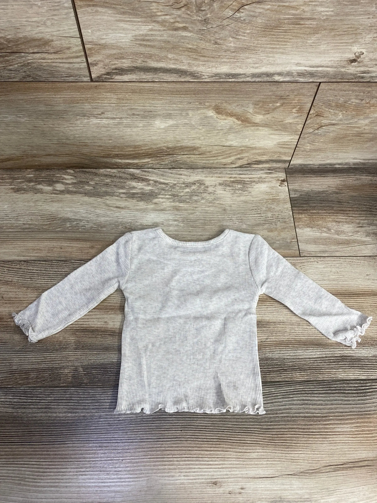Back view of NWT Okie Dokie ribbed long sleeve shirt sz 6m showcasing oatmeal heathered fabric with lettuce-edge hem and cuffs on wood plank floor