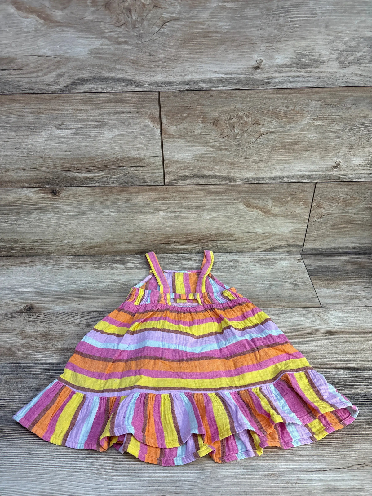 Front view of Cat & Jack striped gauze peplum trim dress in multicolor stripes with a wood-grain background