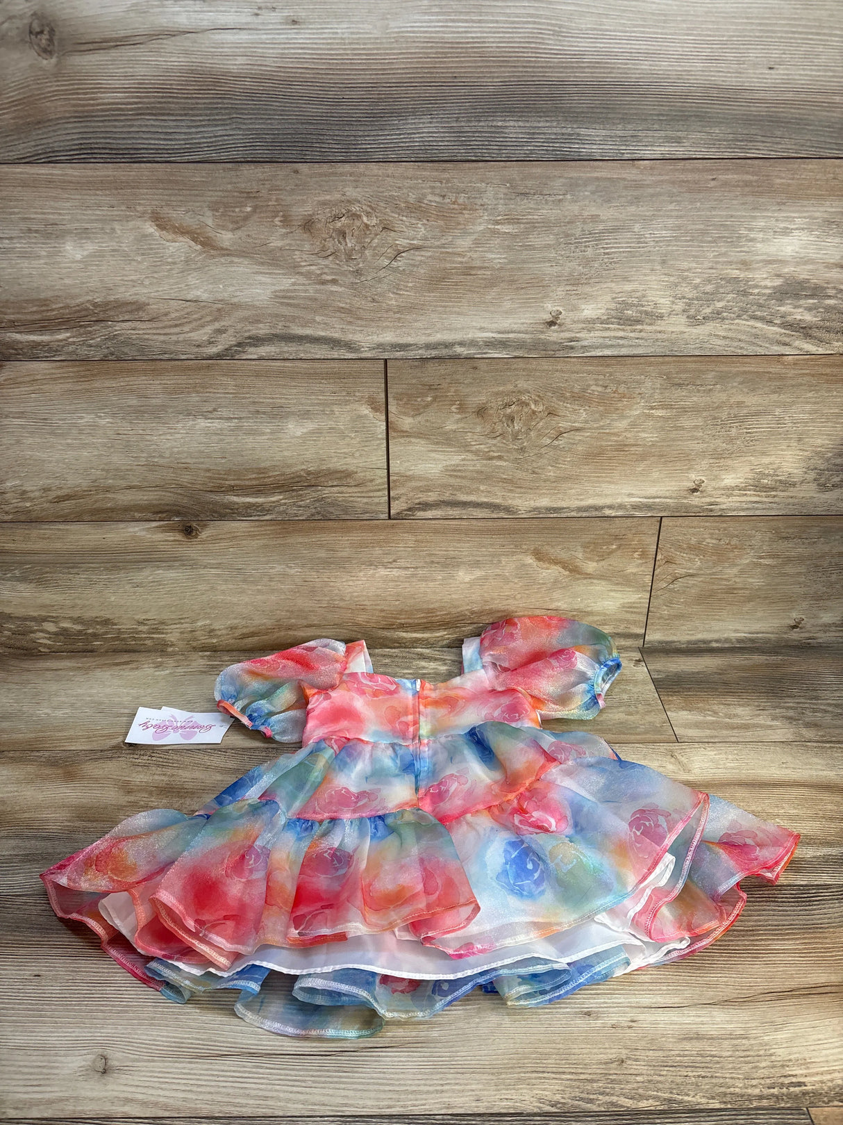 Colorful tulle baby dress with puff sleeves on wood background, gently used kids clothing