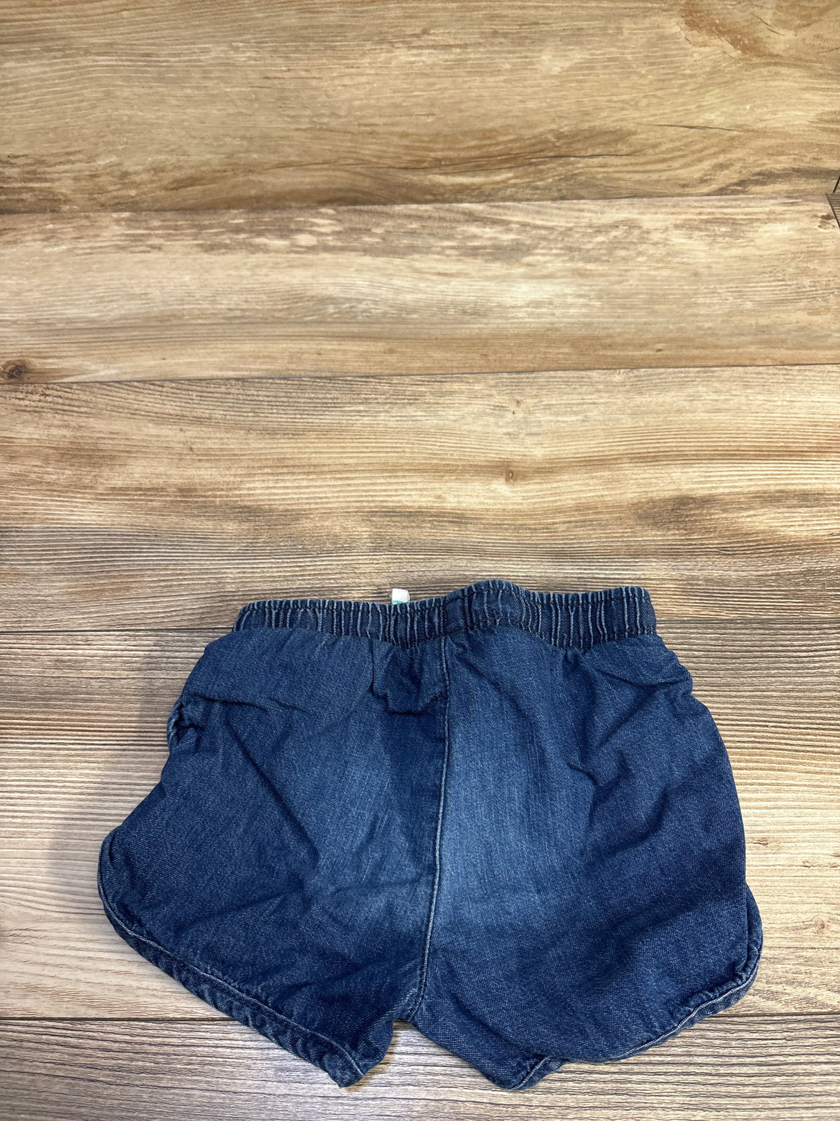 Flat lay of Cat & Jack chambray toddler shorts (size 3T) showing elastic waistband and curved hem on wood background