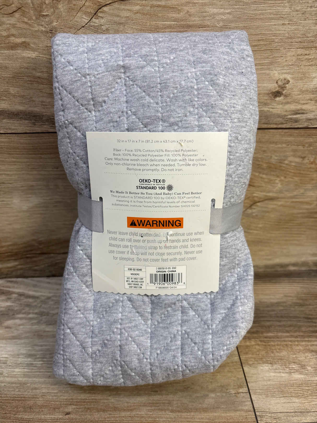 Folded front of Cloud Island changing pad cover in grey showing quilted stitching and size 32x17x7 in on wood