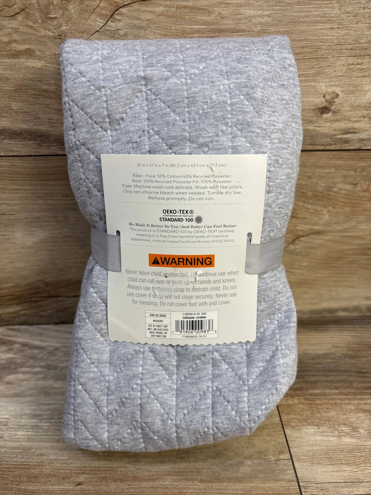 Folded front of Cloud Island changing pad cover in grey showing quilted stitching and size 32x17x7 in on wood