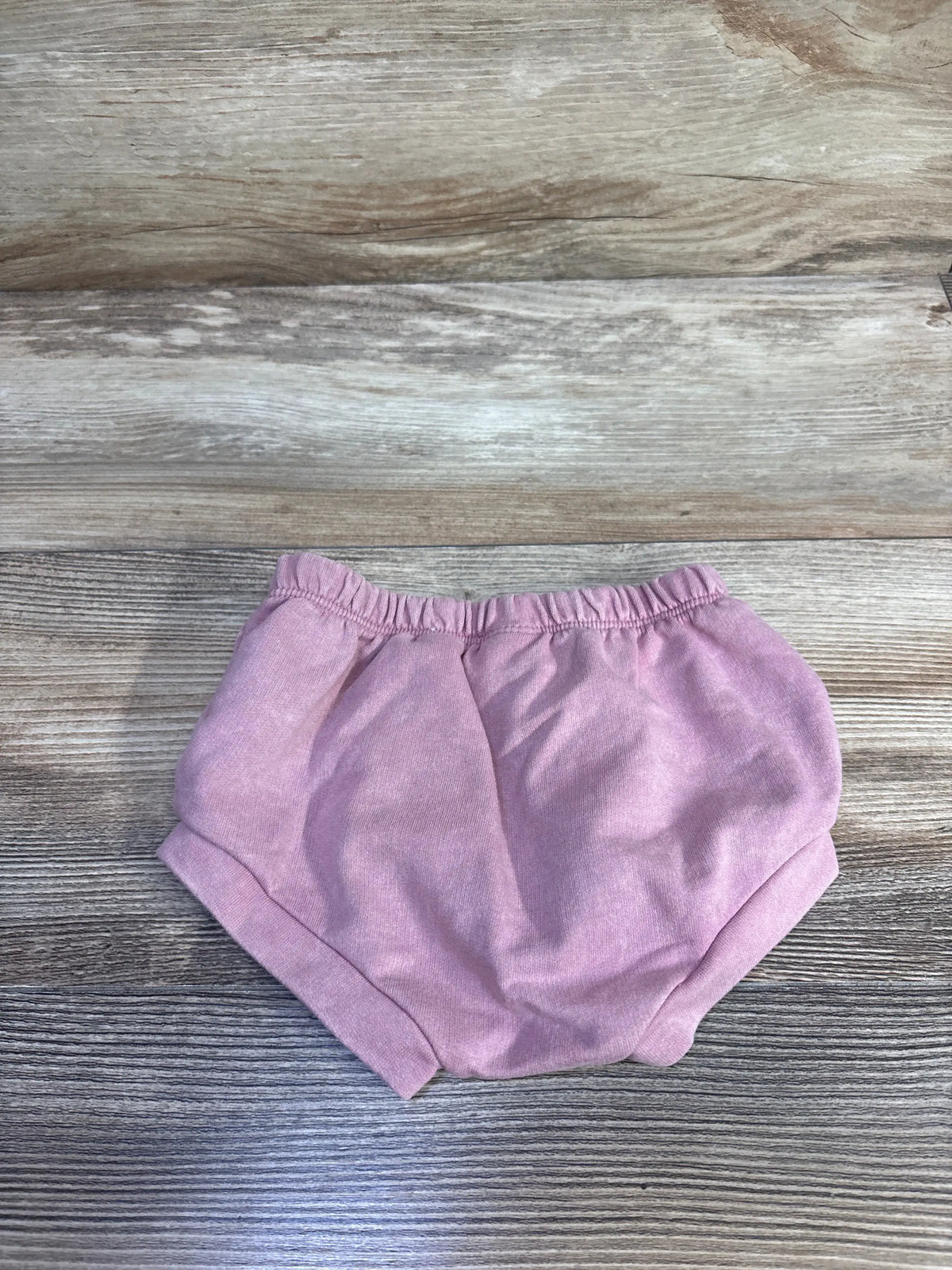 Front view of Cat & Jack pink bloomers, size 3-6 months, showing relaxed fit, elastic waistband and leg openings on wood