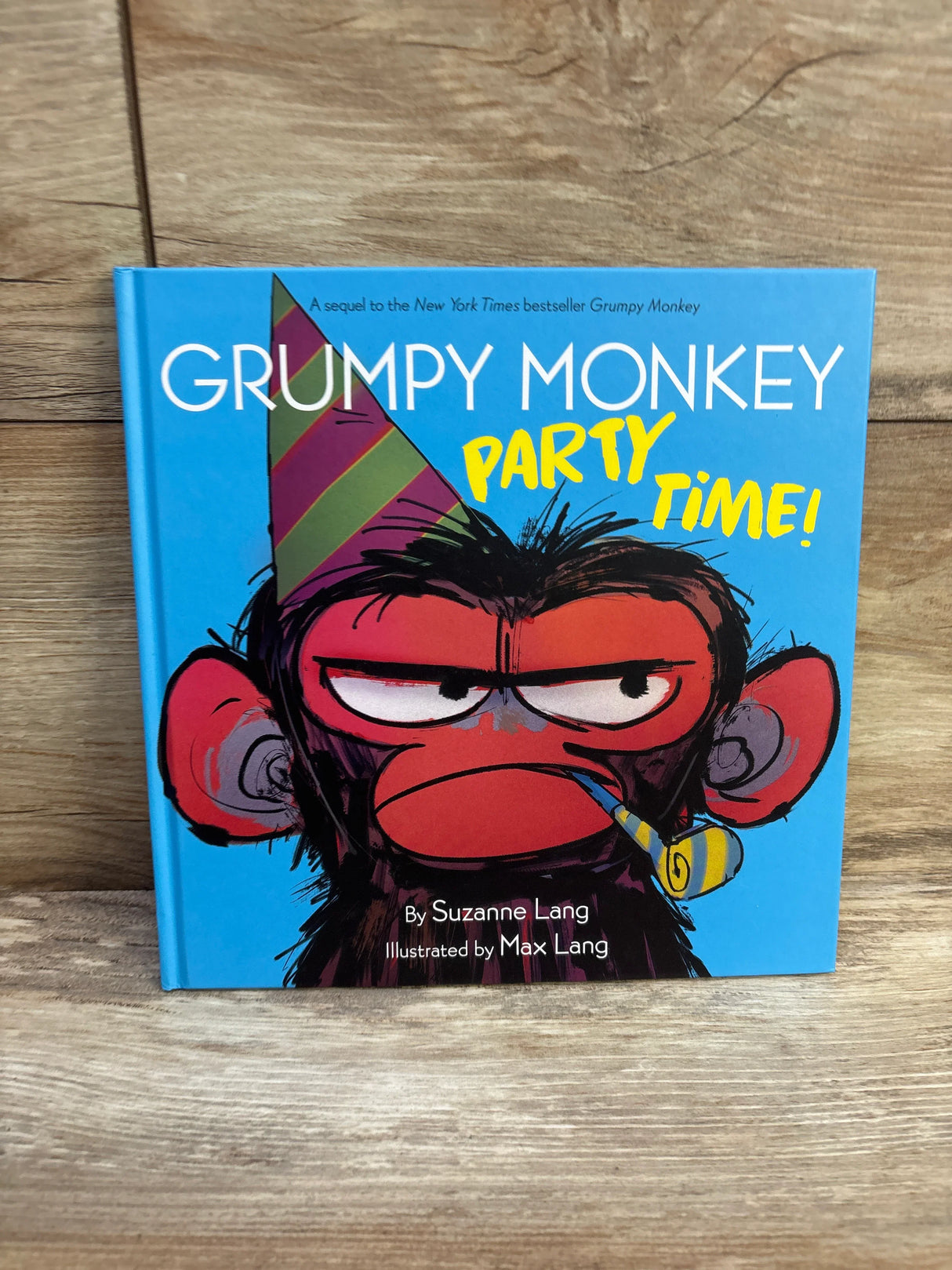 Front cover of Grumpy Monkey Party Time! hardcover showing grumpy monkey with party hat and blower on wood background