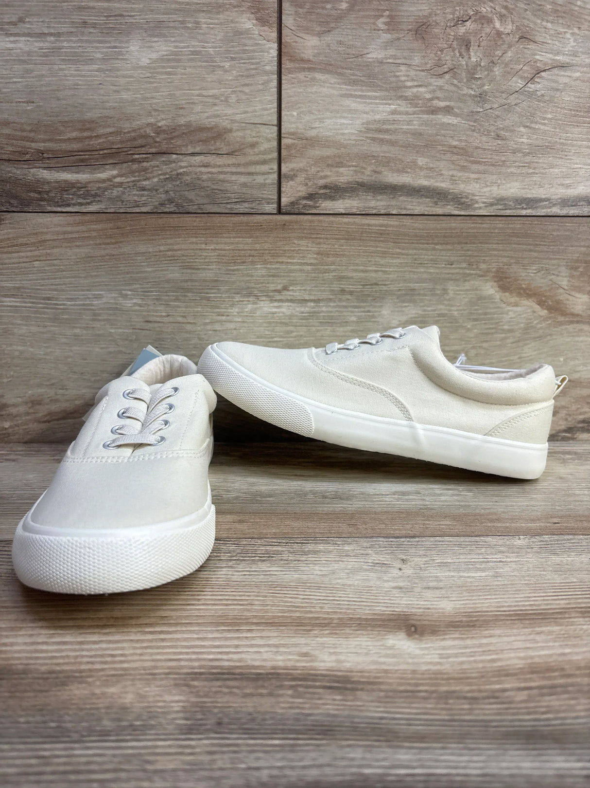 White canvas sneakers for kids with rubber soles on wood background