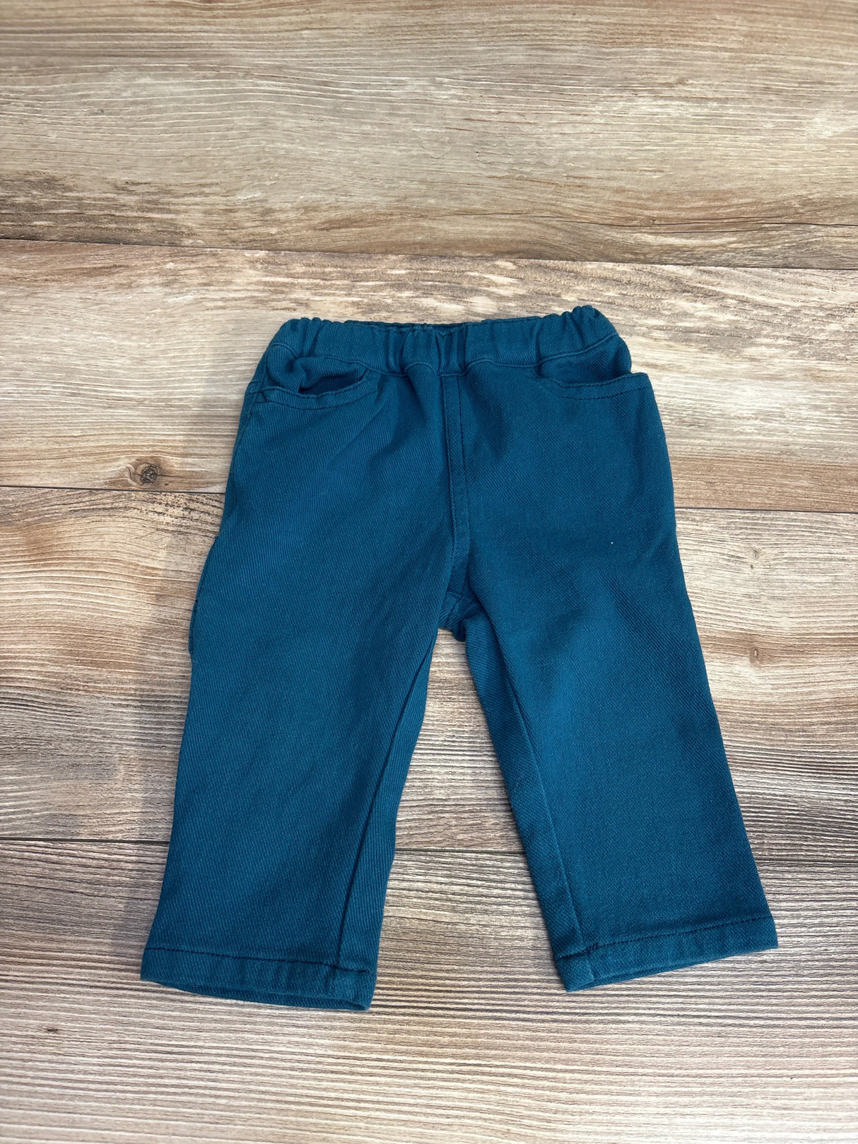 Teal toddler pants with elastic waistband on wood background, kids clothing resale