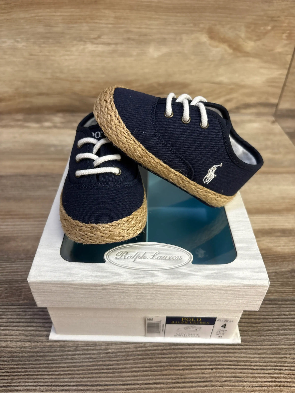 Front and side view of navy Ralph Lauren Bowman lace crib shoes showcasing white laces and braided trim on a shoebox