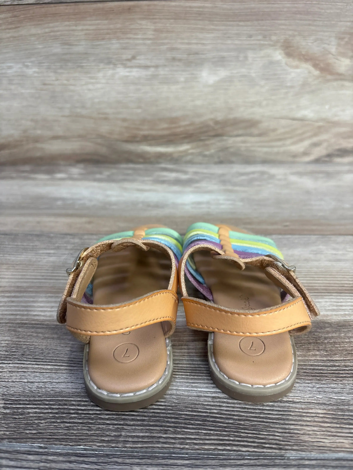 Front view of Cat & Jack Shanel fisherman sandals showcasing tan uppers and multicolored straps on a wood-grain background