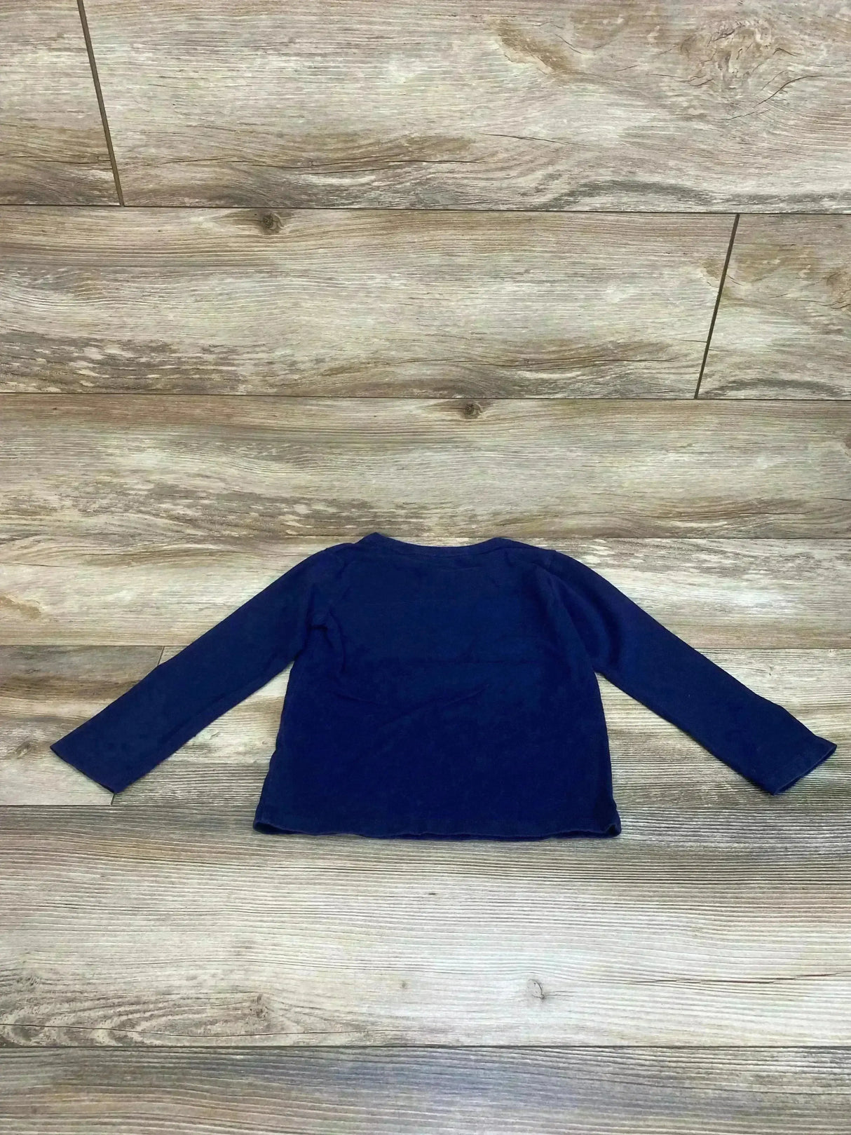 Back view of Children's Place navy long-sleeve toddler shirt size 4T laid flat on wood floor background