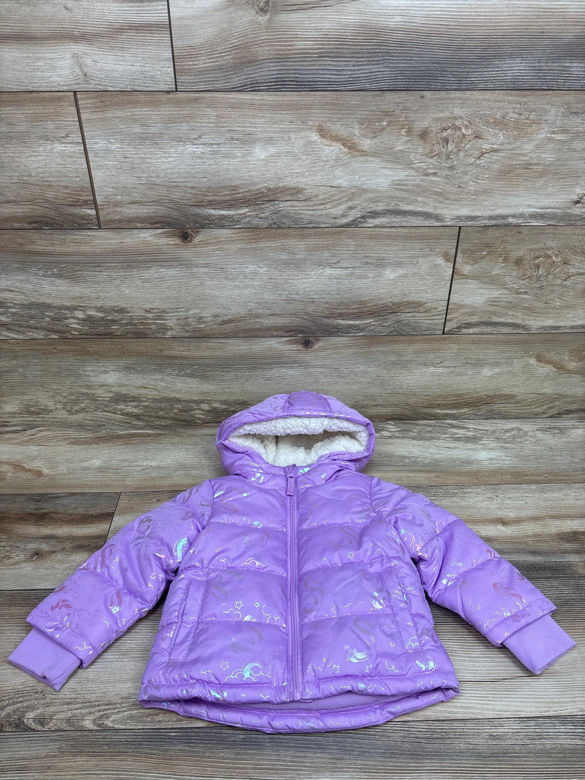 Front view of Okie Dokie purple unicorn puffer jacket, size 18 months, with fleece-lined hood on wood plank background