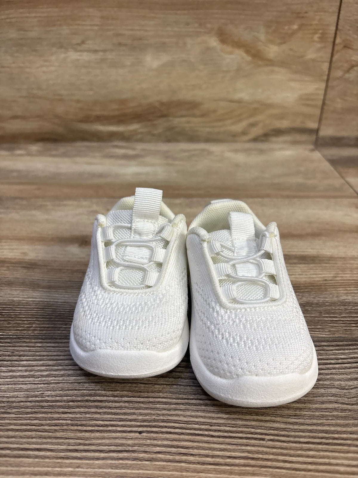 Front view of Morendl white slip-on mesh sneakers in size 4C with textured uppers and white soles on a wood-grain surface