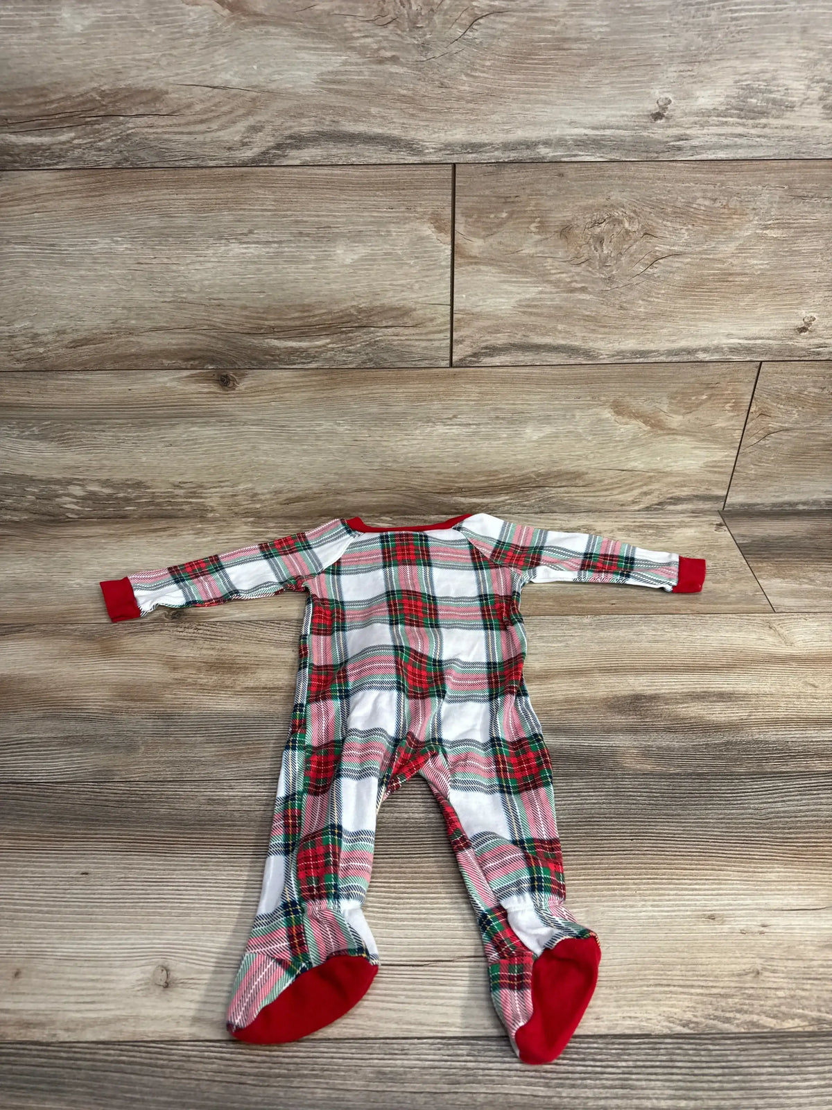 Red green plaid baby footed pajamas on wood floor, holiday kids clothing