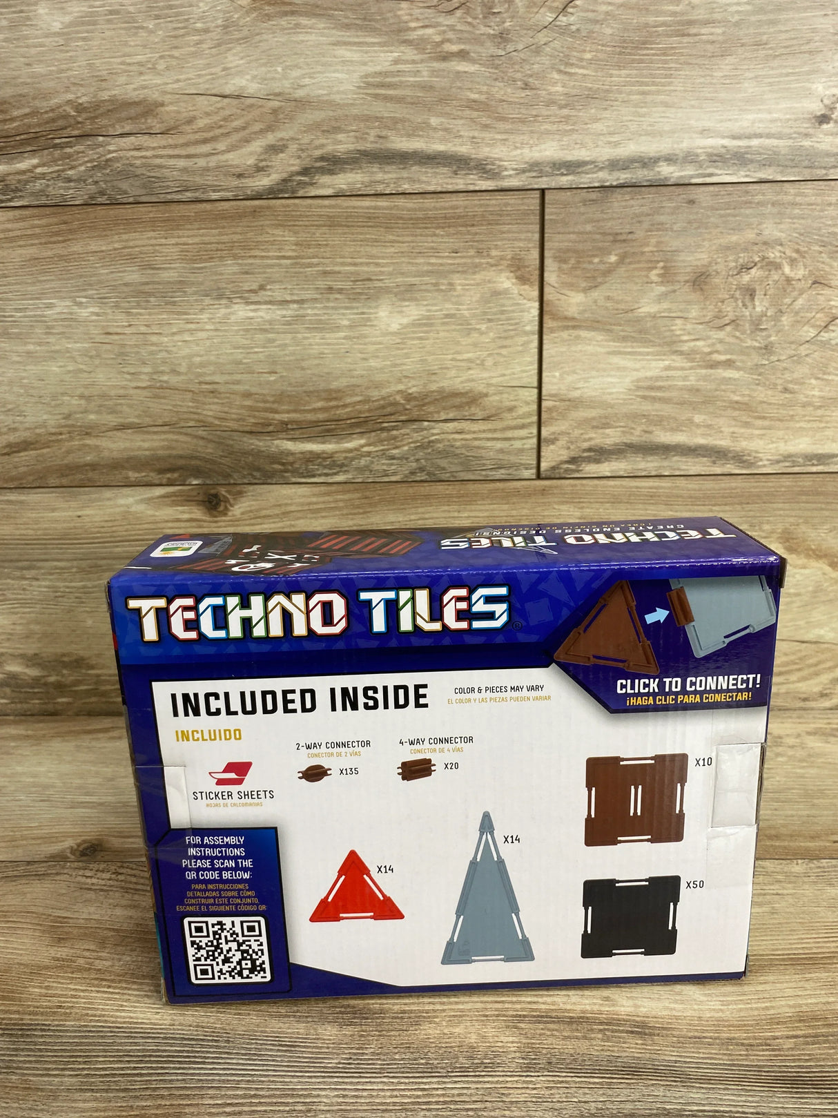 Techno Tiles building set box showing included connectors, triangle and square tile pieces on wood floor.