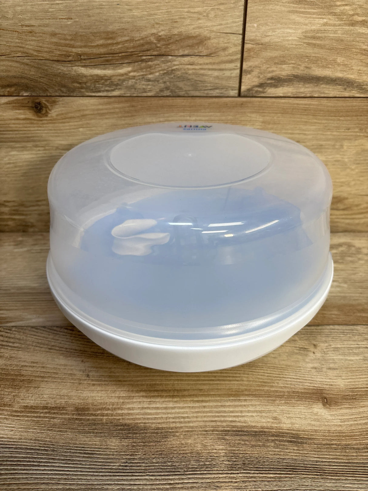 Angled top view of AVENT microwave steam sterilizer showcasing translucent lid and white base on wooden background