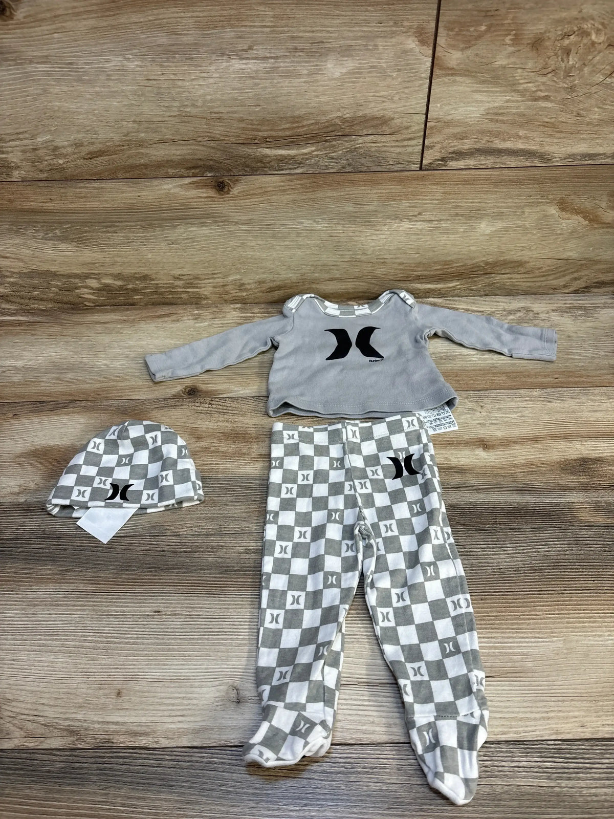 Flat lay of Hurley gray 3-piece checkered layette set size 3M showing logo top, checkered footed pants and hat