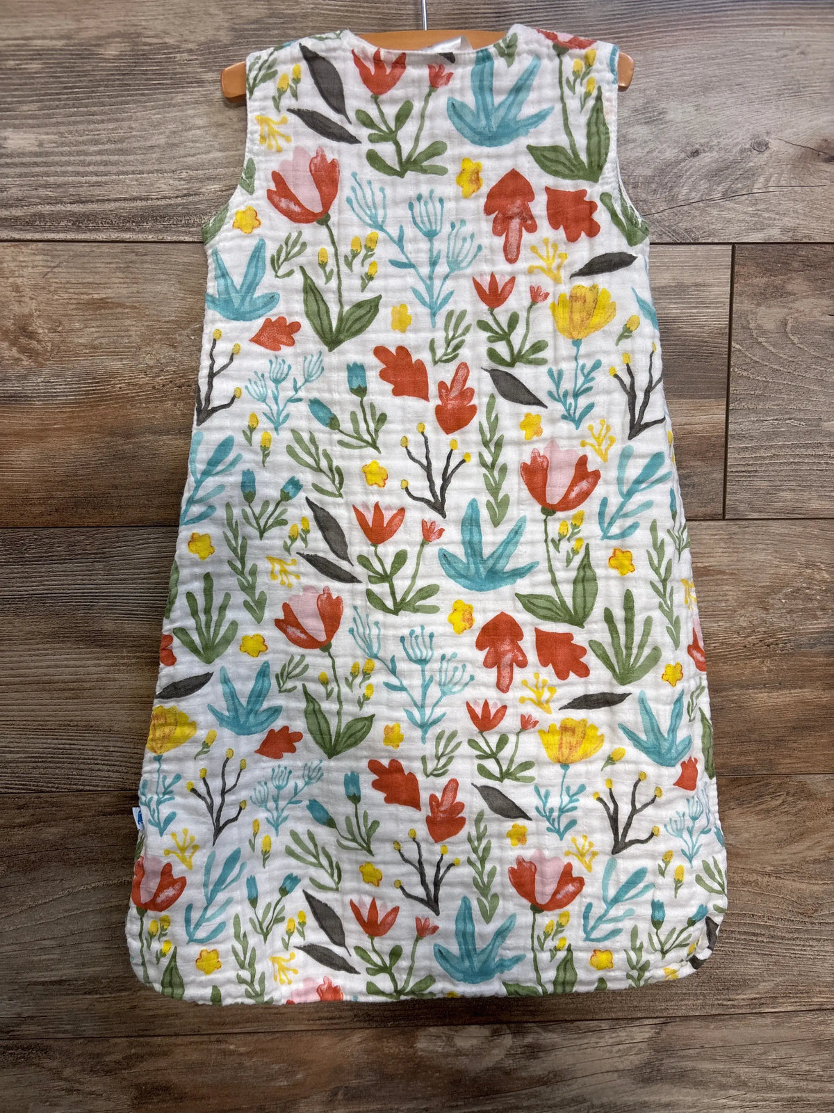 Front view of Little Unicorn cotton muslin sleep sack showcasing colorful floral print on white muslin, size small for 0 to 6 months