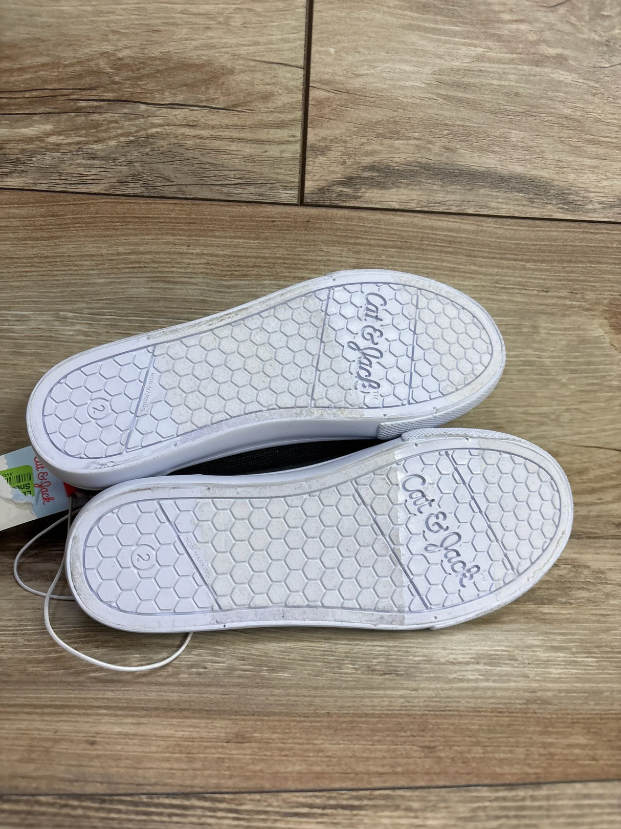 Sol soles of Cat & Jack kids' shoes size 2 on wooden floor, children's casual footwear