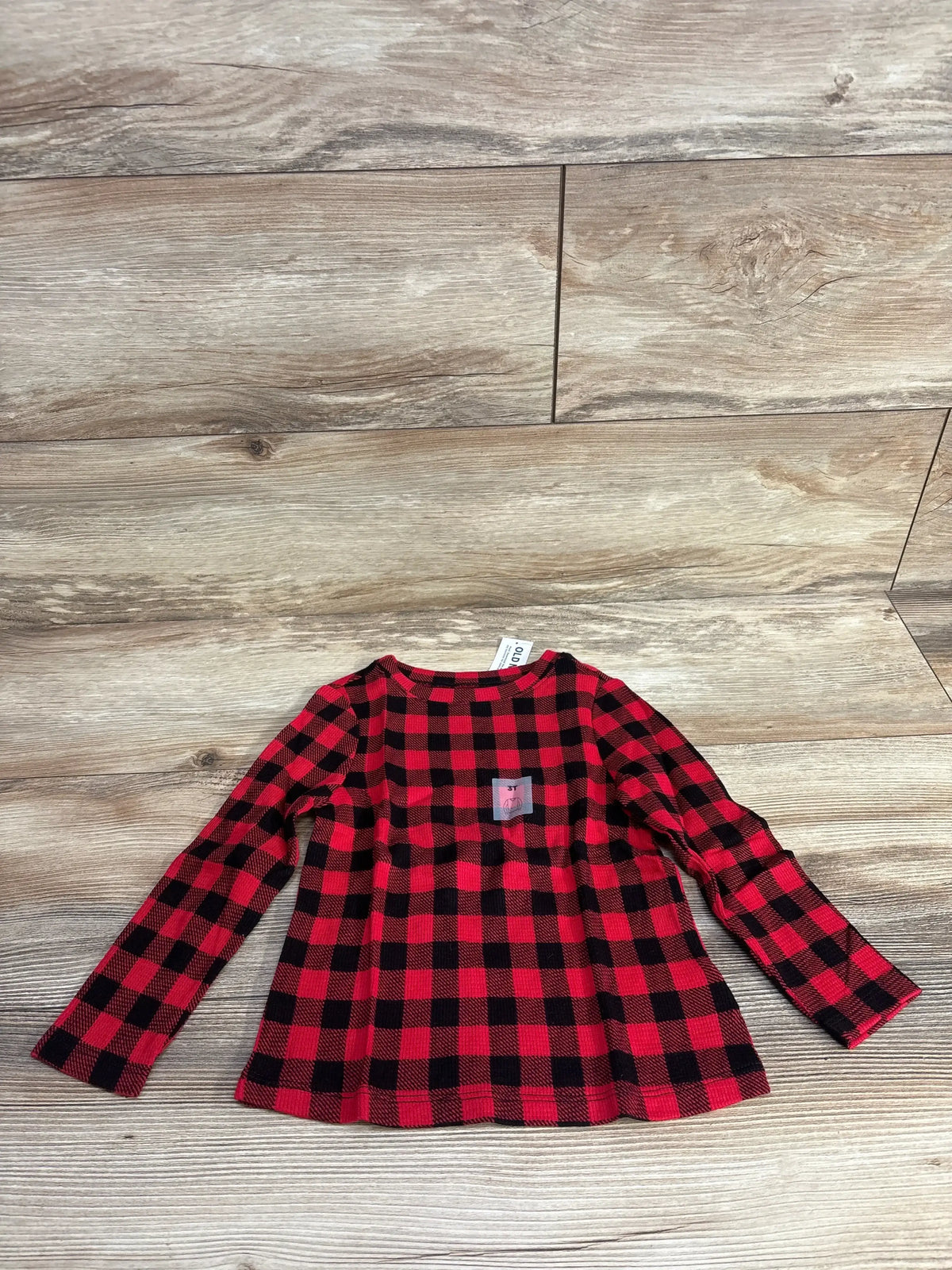 Red and black plaid long sleeve toddler shirt on wood background