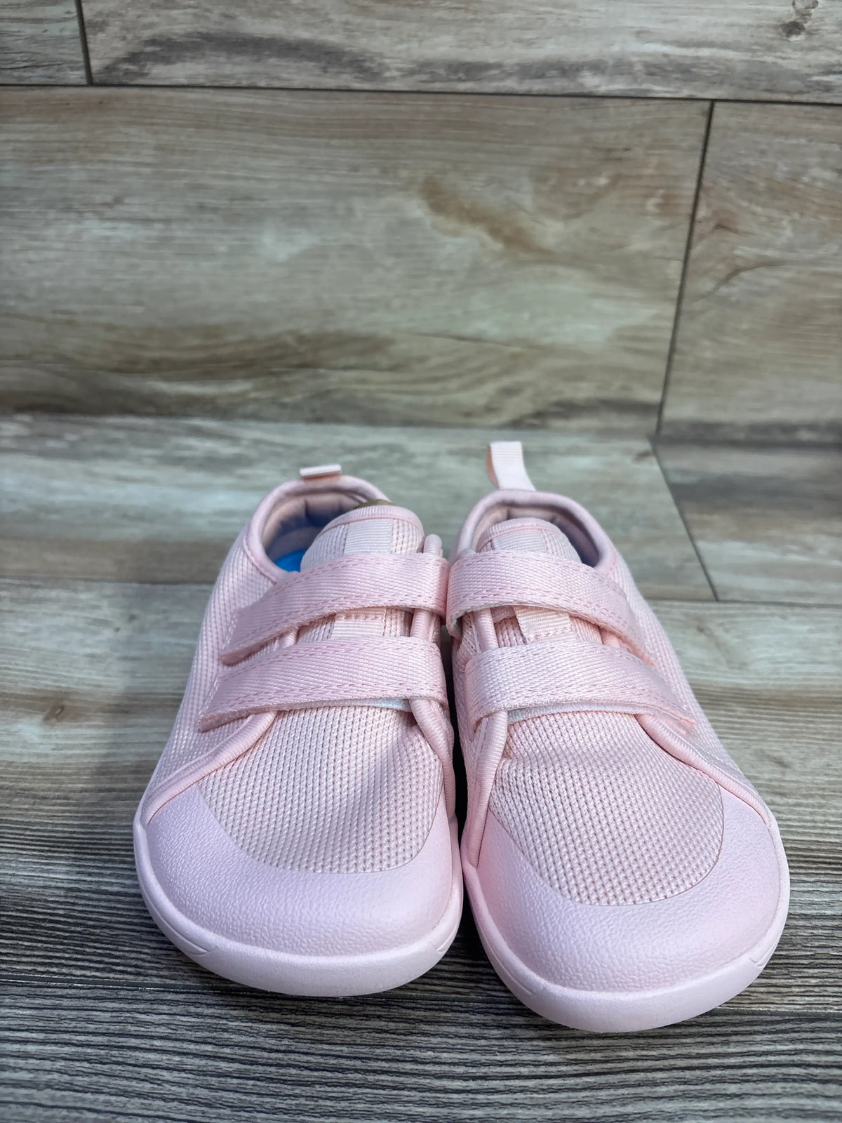 Front view of pink NEW WHITIN wide barefoot sneakers showcasing two hook-and-loop straps on a wood-look floor