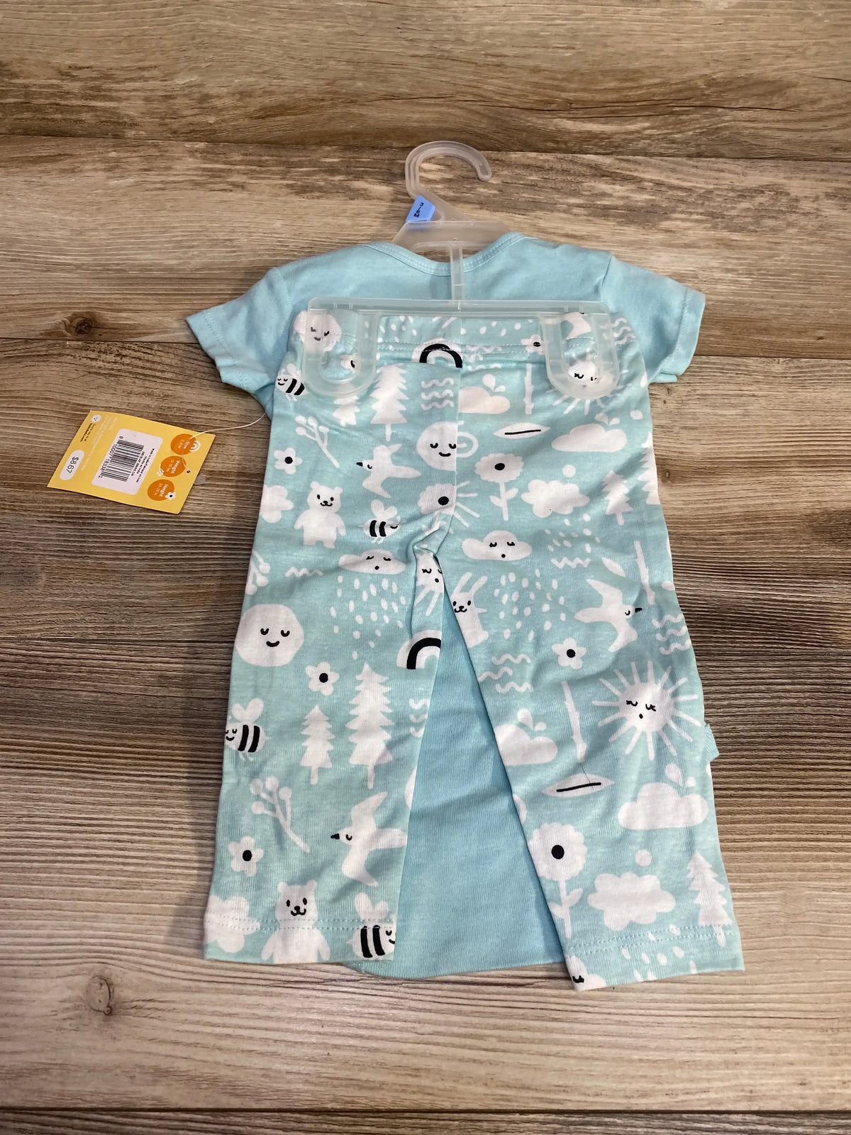 Back view of Hello Bello blue 2-piece baby bodysuit and pants set showcasing rear snap opening and white cloud and animal print on wood surface