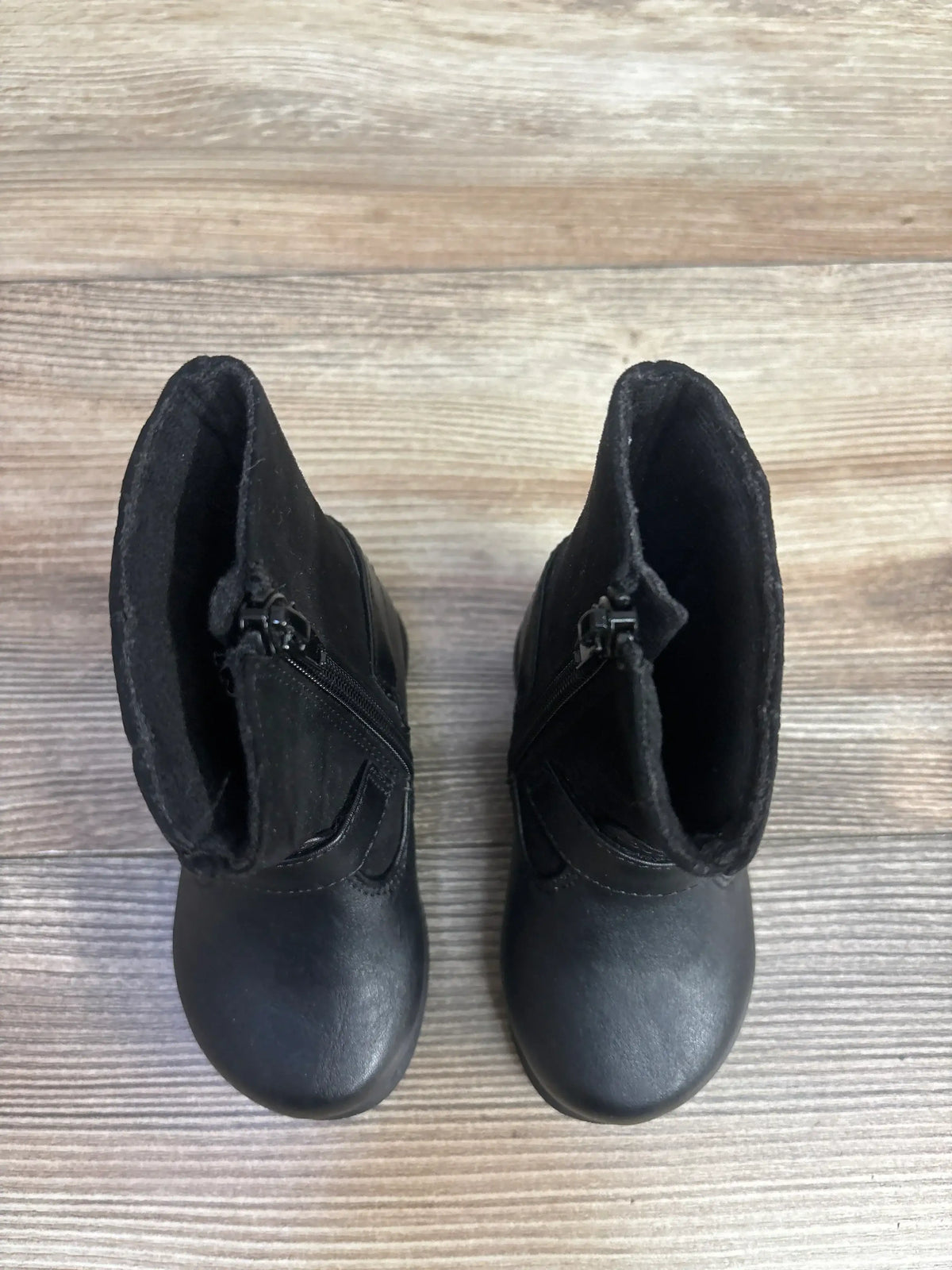 Top-down view of Rachel Shoes Aubriella black toddler boots size 5C showcasing side zippers and rounded toes on light wood floor