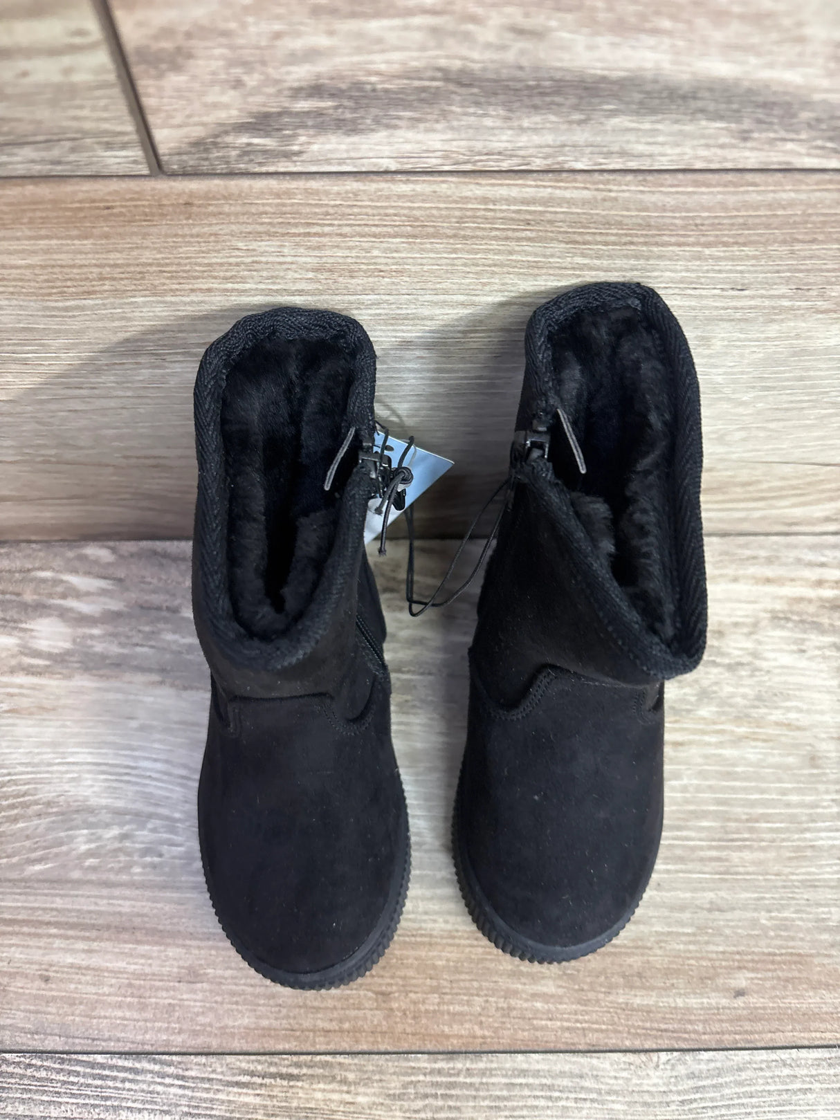 Black toddler boots with fur lining and side zipper on wood floor