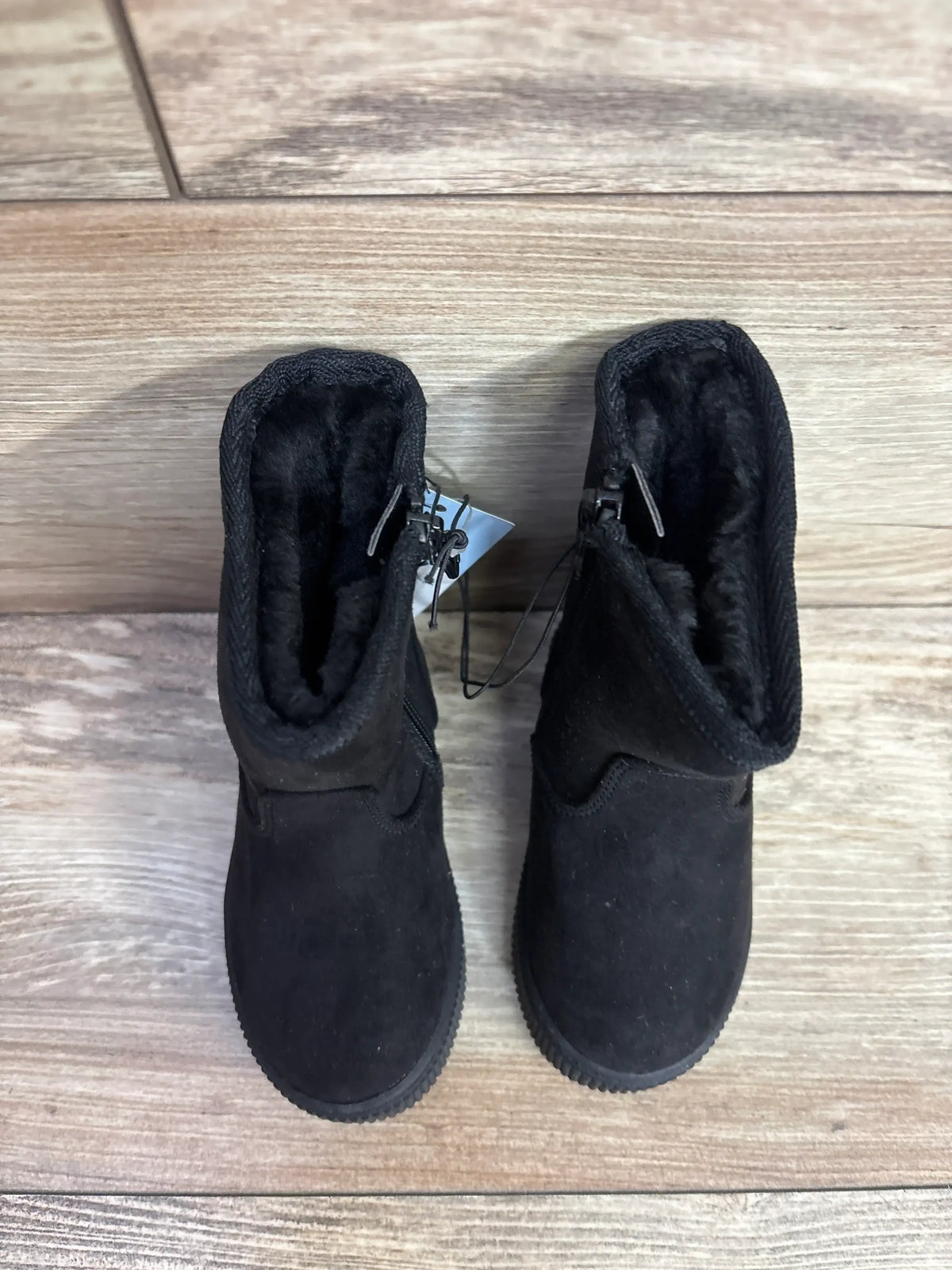 Black toddler boots with fur lining and side zipper on wood floor