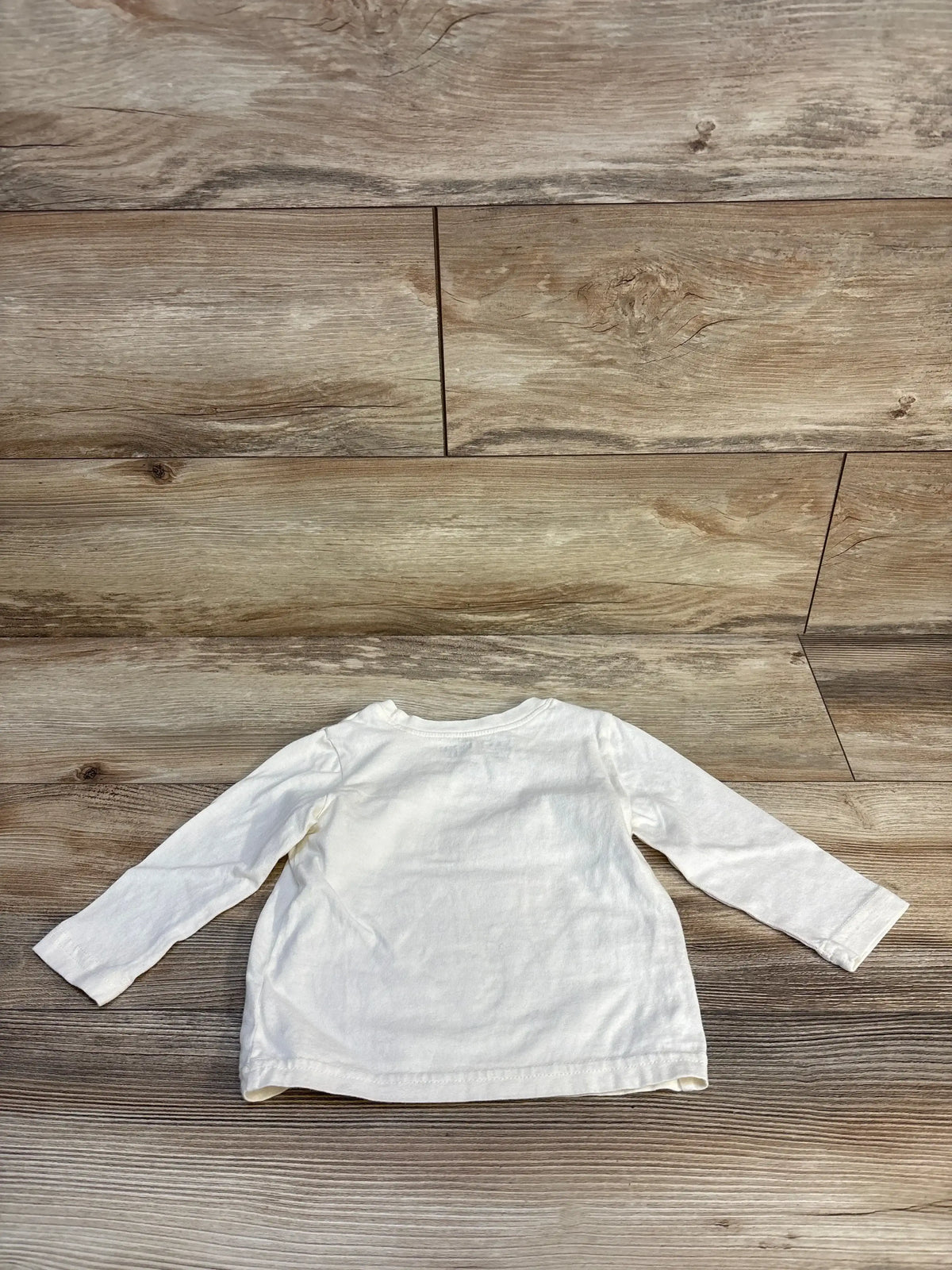 Back view of Disney Jumping Beans long-sleeve infant shirt (12M) showing plain beige back laid flat on wood floor