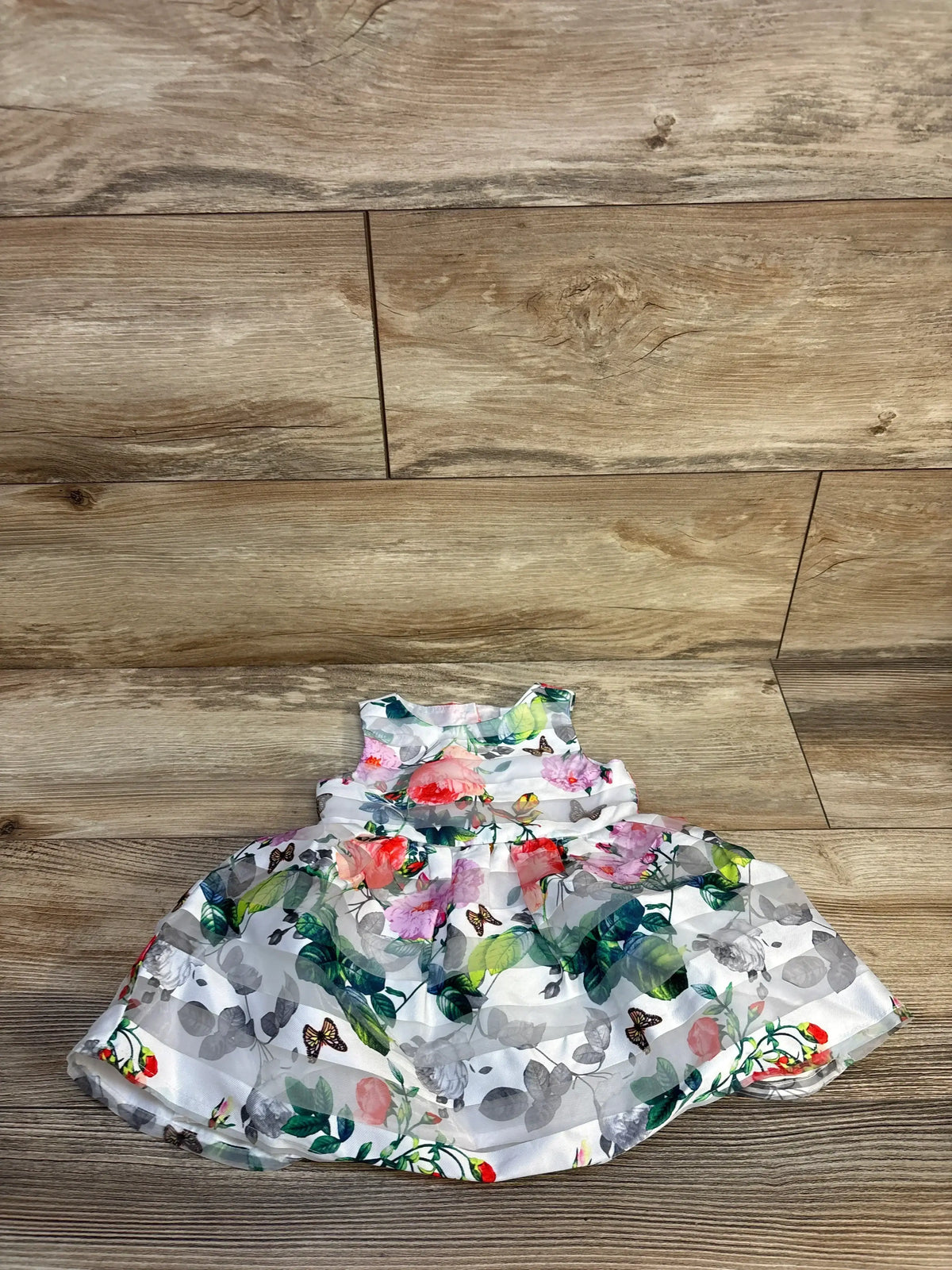 Baby floral dress with butterflies on wood floor, kids clothing resale