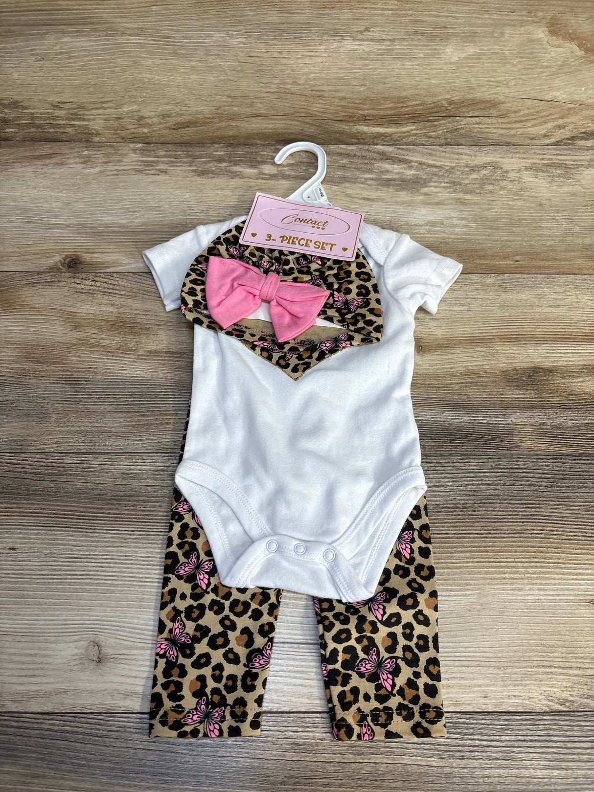 White baby onesie with leopard print butterfly pants & pink bow, 3-piece set on hanger