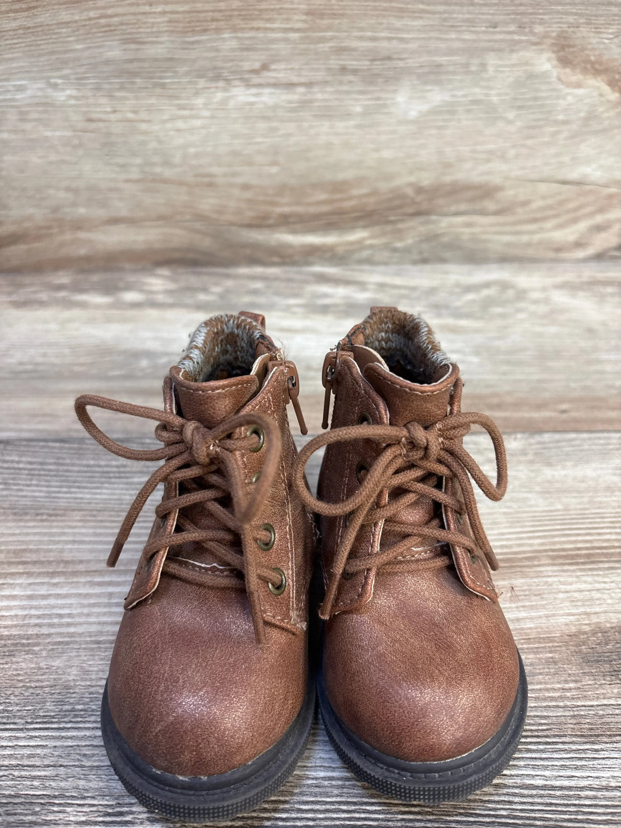 Brown toddler lace-up boots with faux fur lining on wooden background