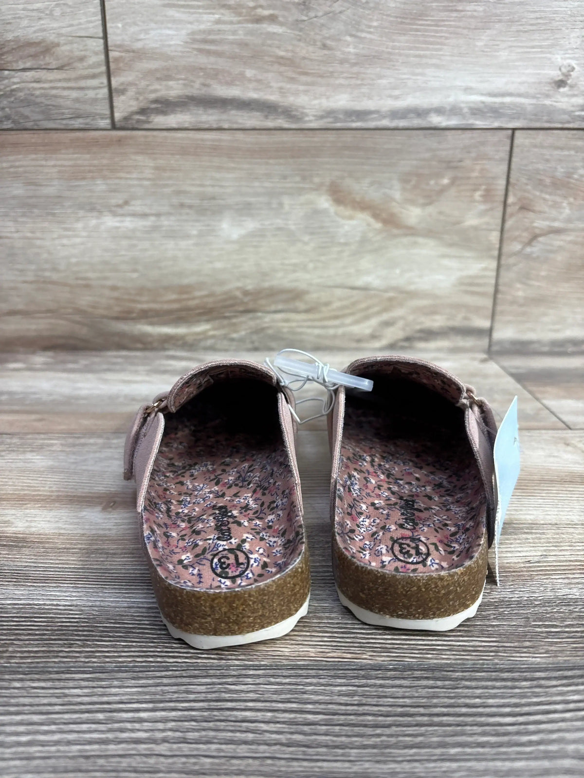 Top view of Cat and Jack Perry clogs in blush, size 13C, showcasing floral footbeds and hook-and-loop closures on a wood floor
