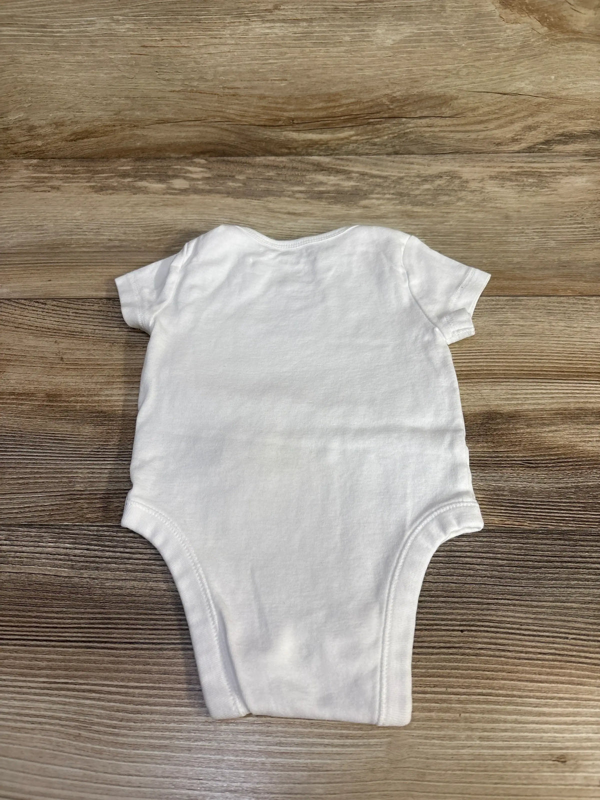 Back view of white Old Navy x Disney Mickey Mouse bodysuit with short sleeves on a wood background