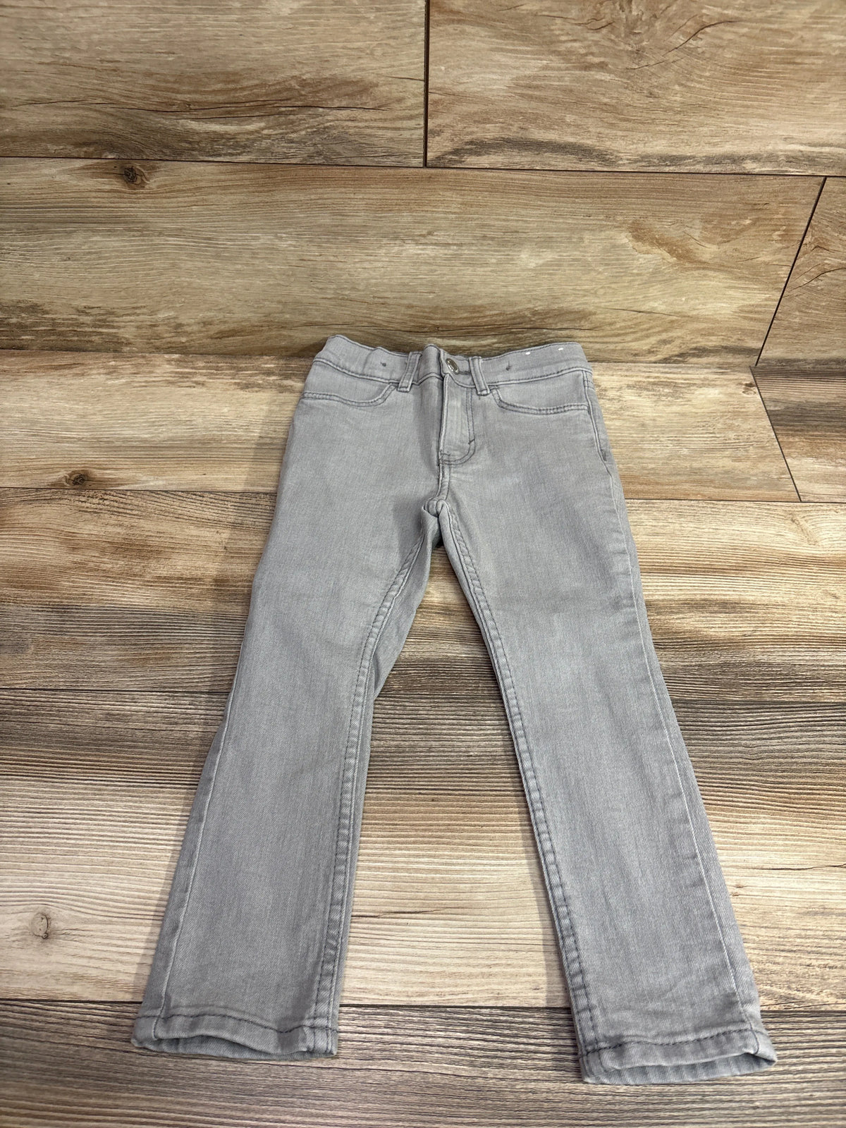 Grey H&M skinny denim jeans for toddlers, size 4T, laid flat on a wood background.