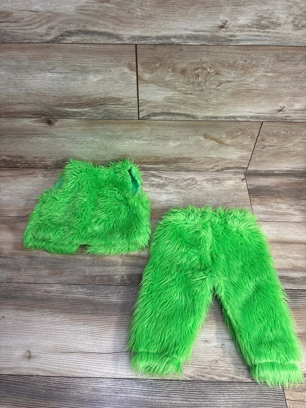 Bright green fuzzy kids costume set with pants and top on wood floor