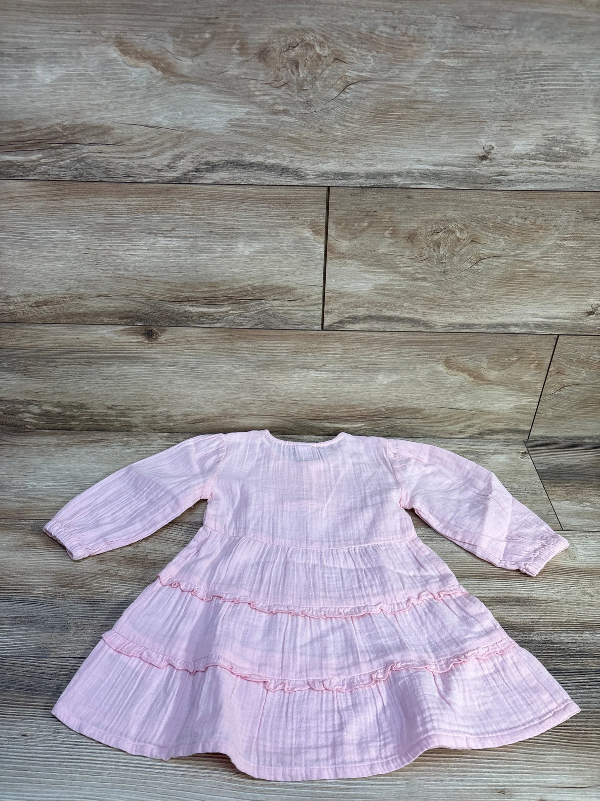 Flat lay of pink Old Navy long-sleeve tiered dress showcasing double-weave fabric and ruffled tiers on light wood floor
