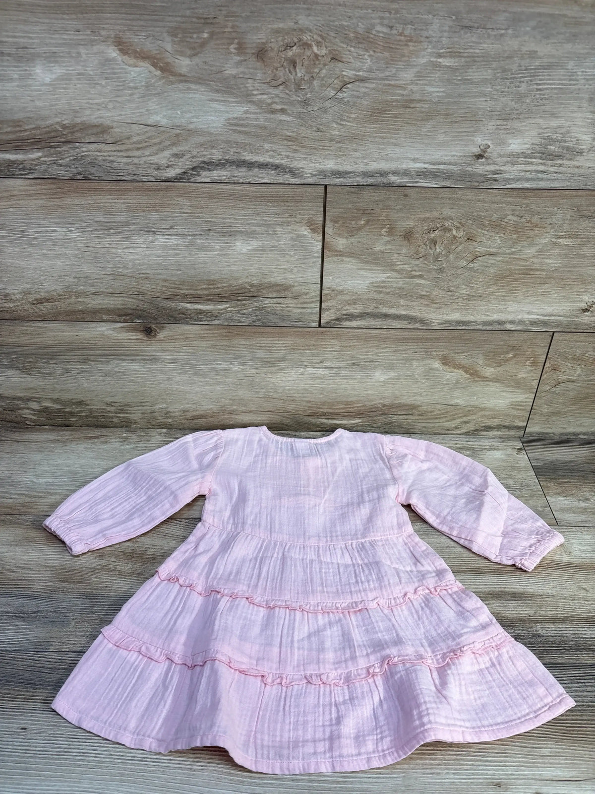 Flat lay of pink Old Navy long-sleeve tiered dress showcasing double-weave fabric and ruffled tiers on light wood floor