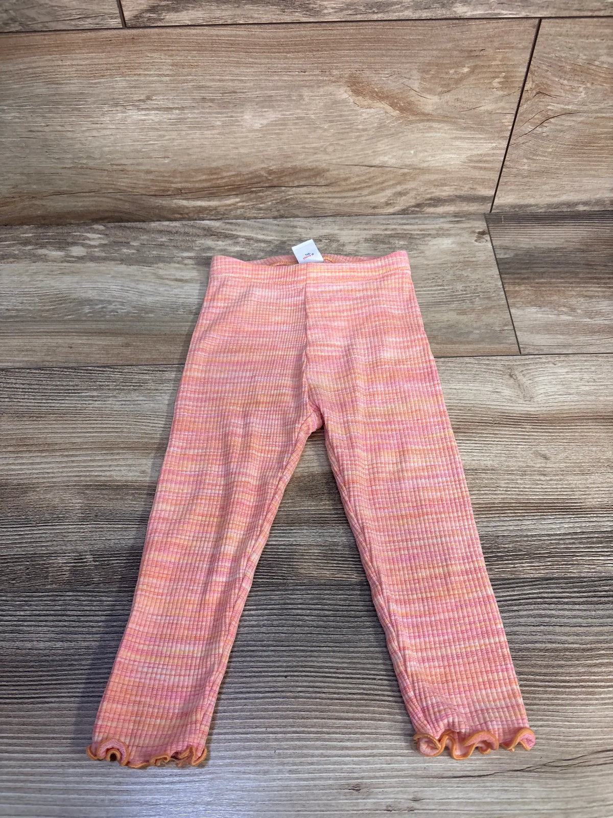 Front view of Old Navy orange ribbed leggings, size 18-24 months, with elastic waistband and flared hems on wood floor