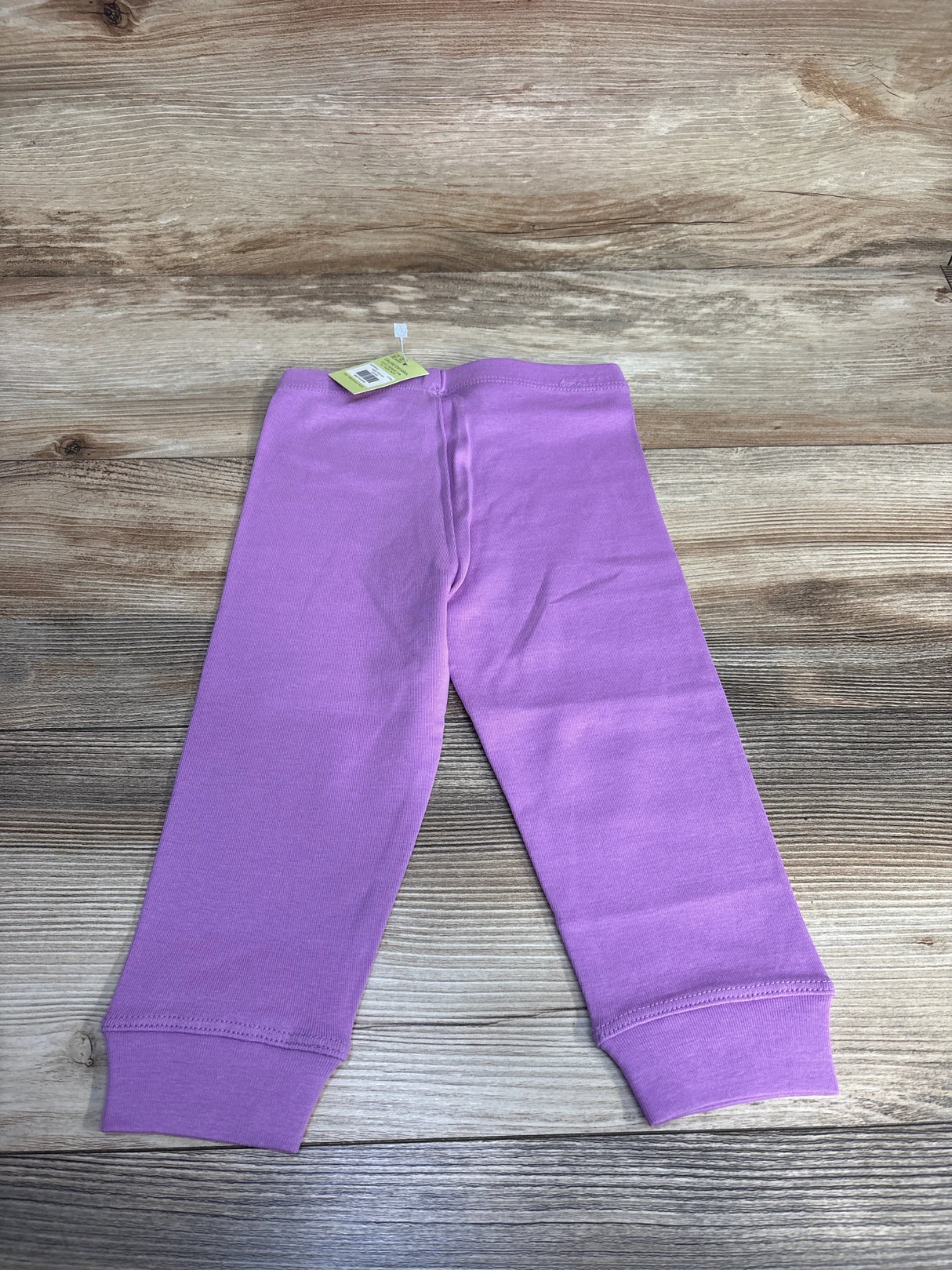 Purple toddler leggings with tag on wood background