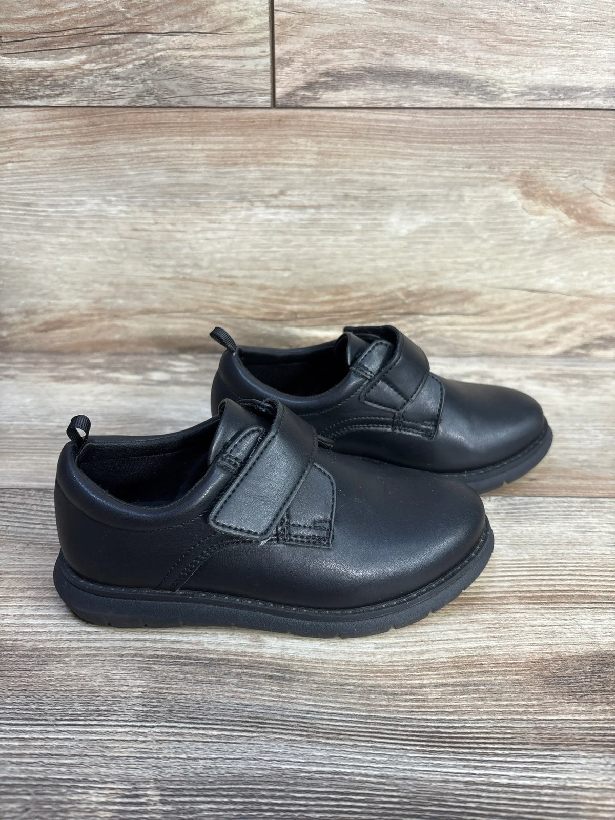 Pair of black Wonder Nation oxford dress shoes for children on a wood grain background.